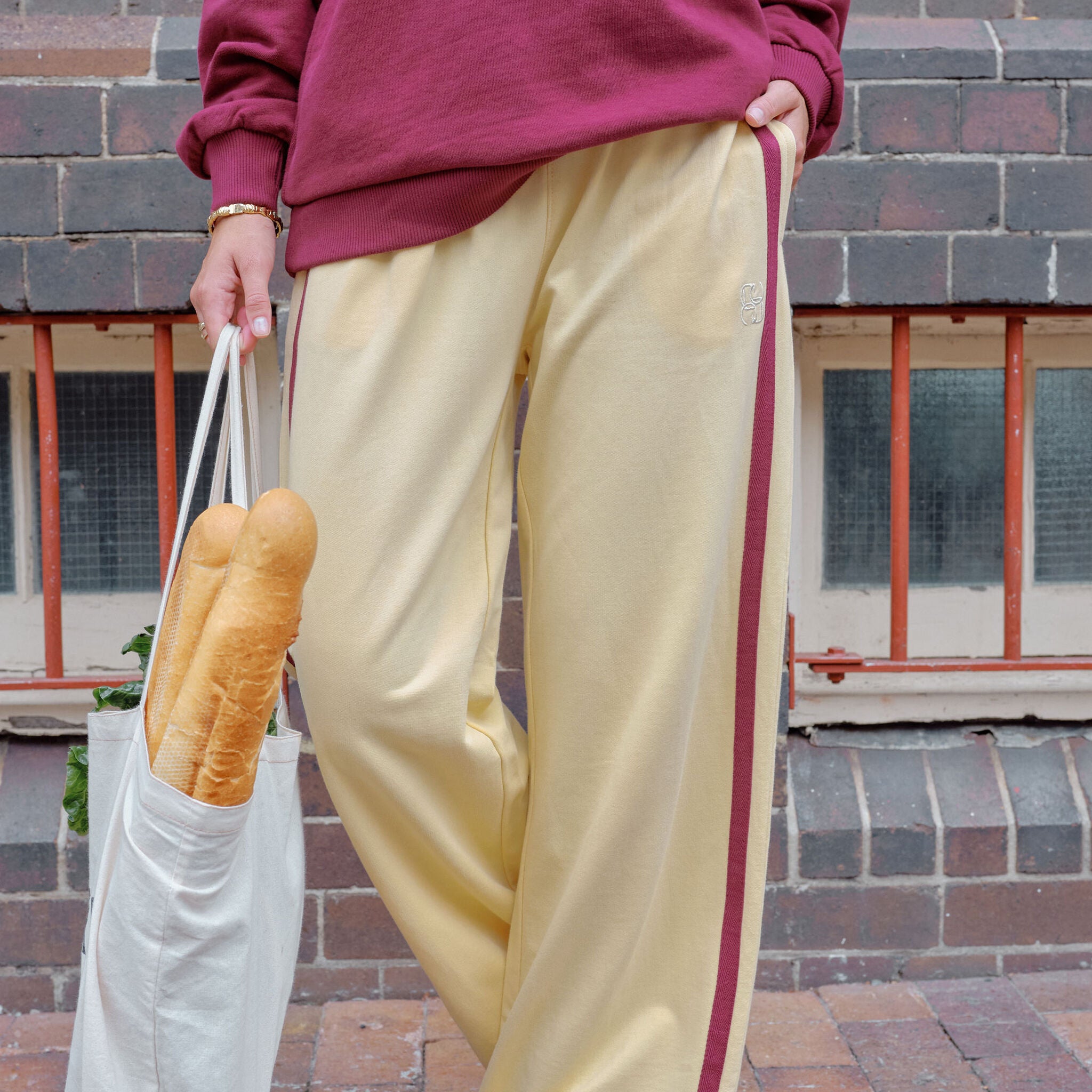 Woman walking in bright blue wide leg track pants with white side stripe crossing street