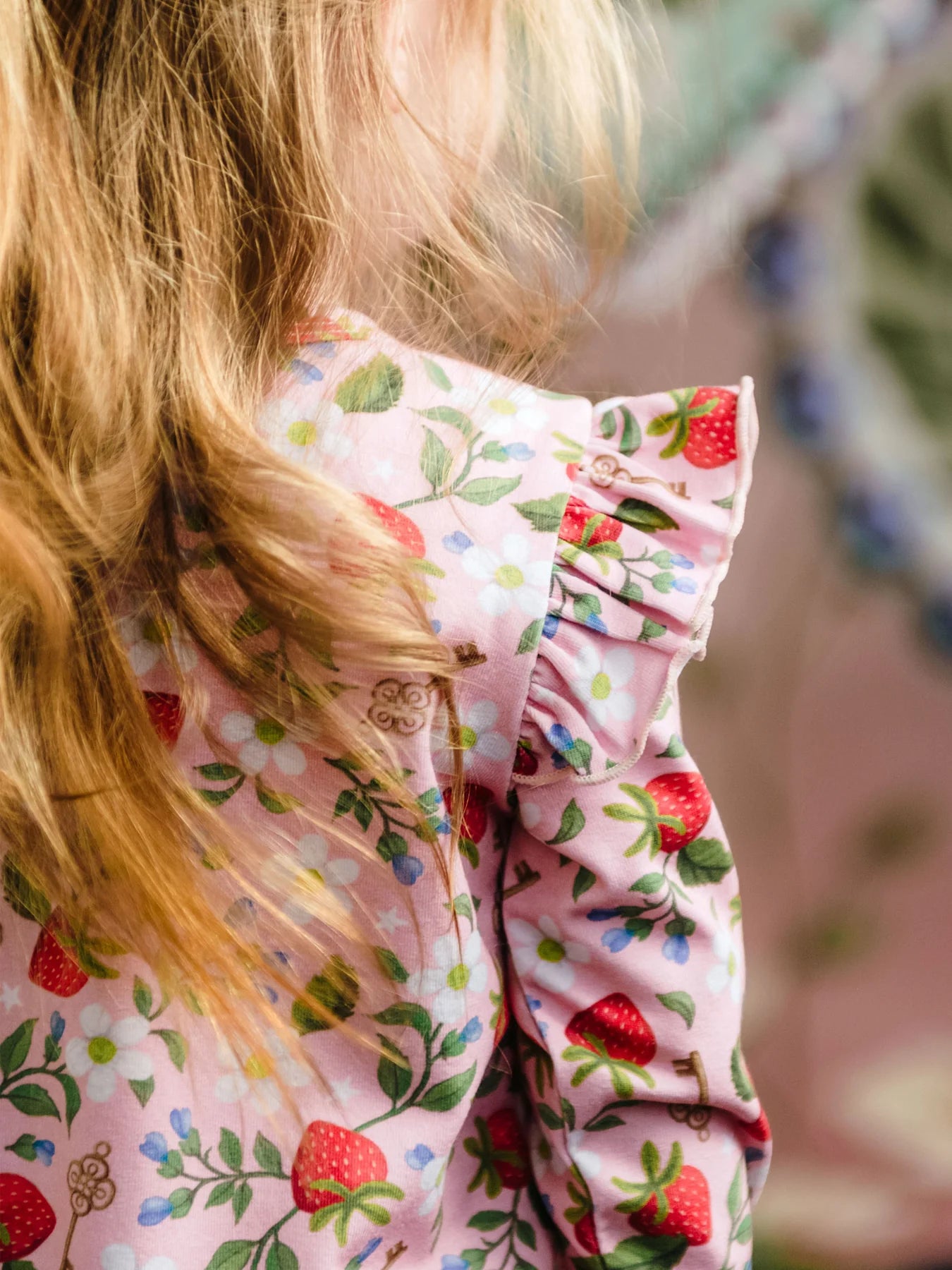 Close-up of a child wearing a pink floral onesie with strawberries and flowers