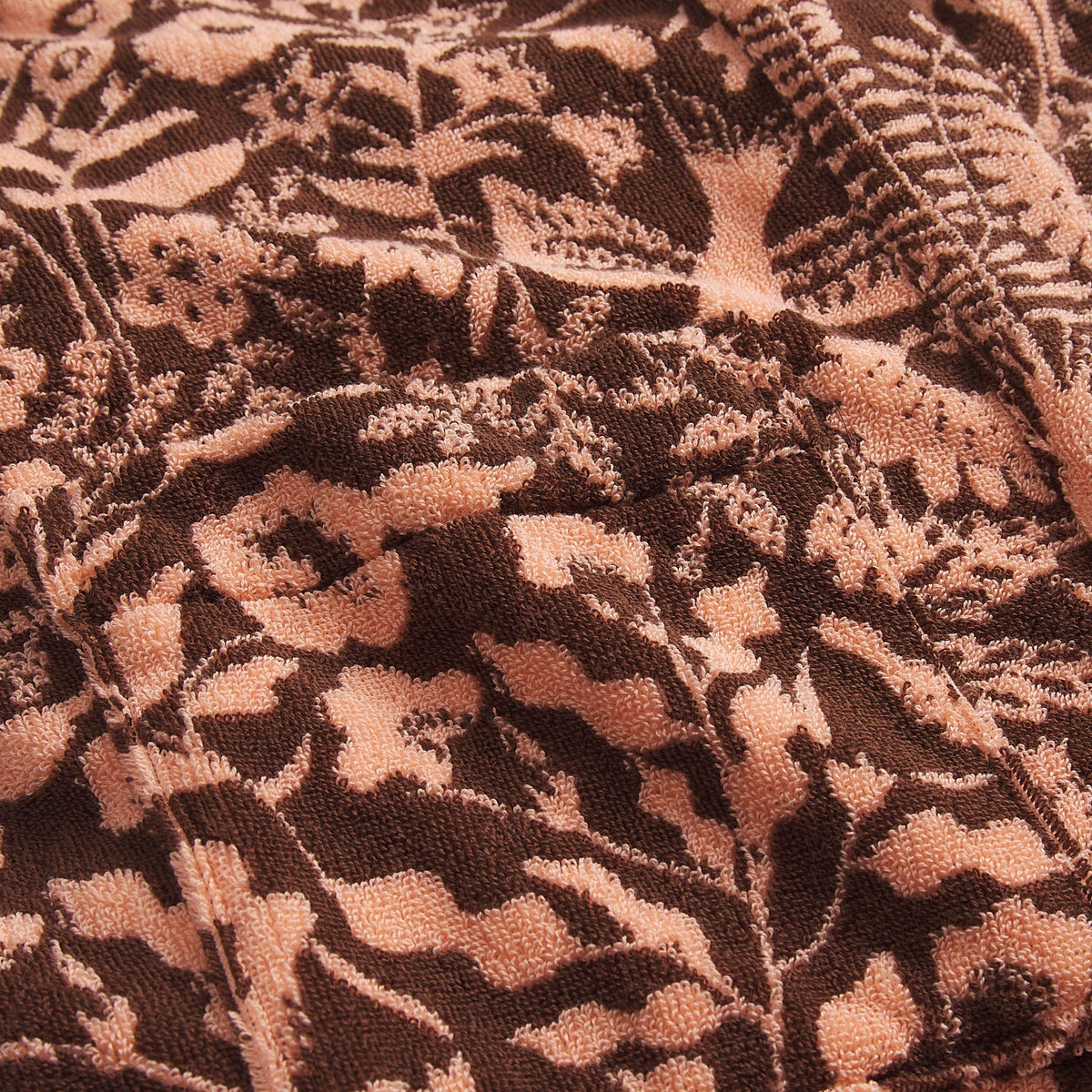 Close-up detail of the peach and dark brown botanical floral jacquard towelling fabric texture