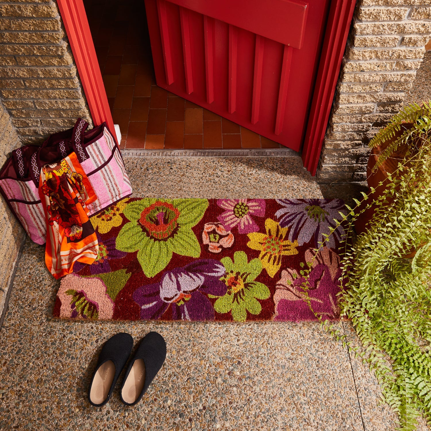 Ines Door Runner by Sage & Clare with vibrant floral pattern placed at front entrance with red door