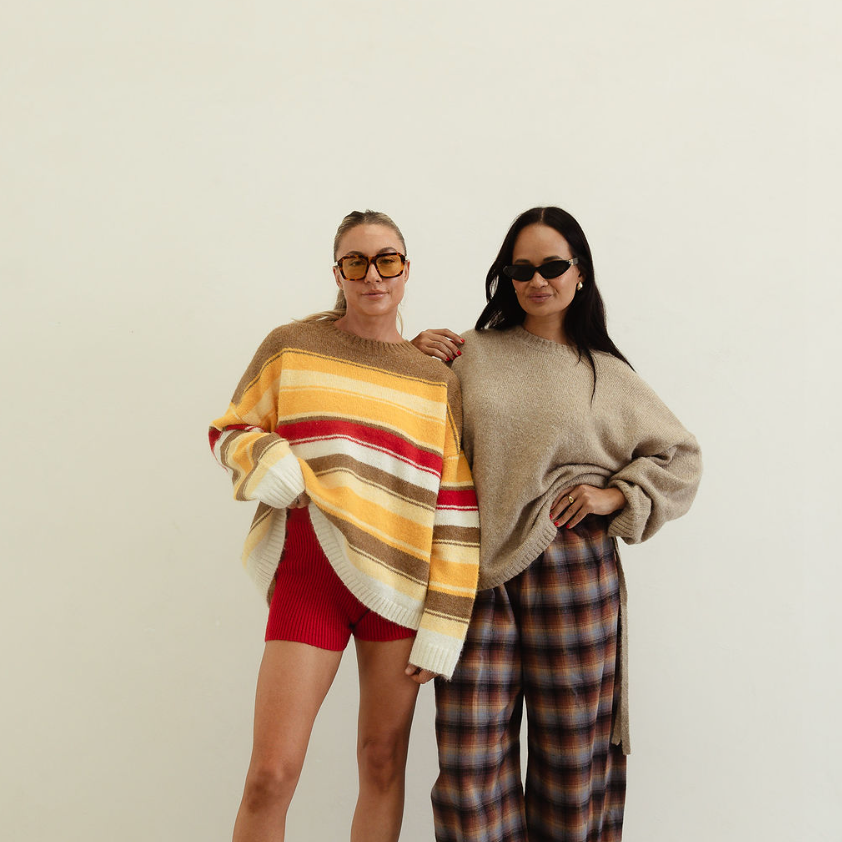 Two women modeling autumn stripe knit sweater alongside neutral coordinating knitwear pieces