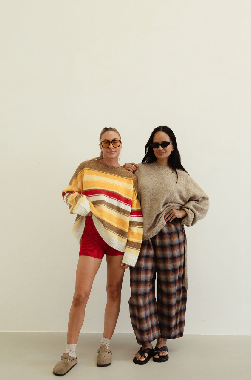 Two women modeling autumn stripe knit sweater alongside neutral coordinating knitwear pieces