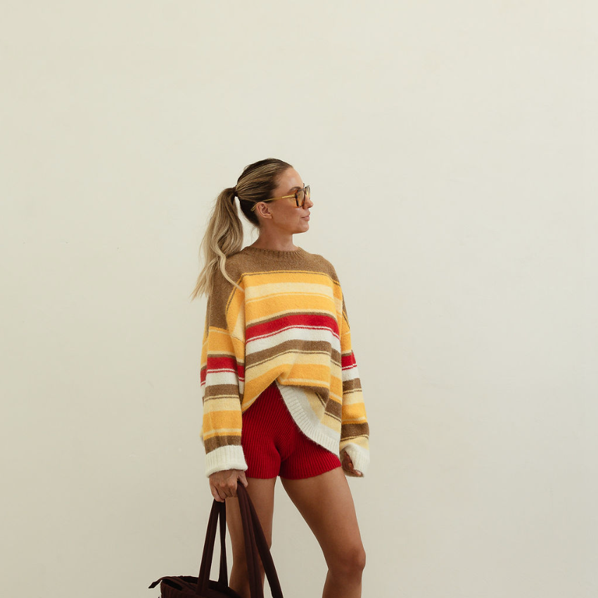 Side profile of model wearing Isabel Knit autumn stripe sweater with long sleeves and crew neckline