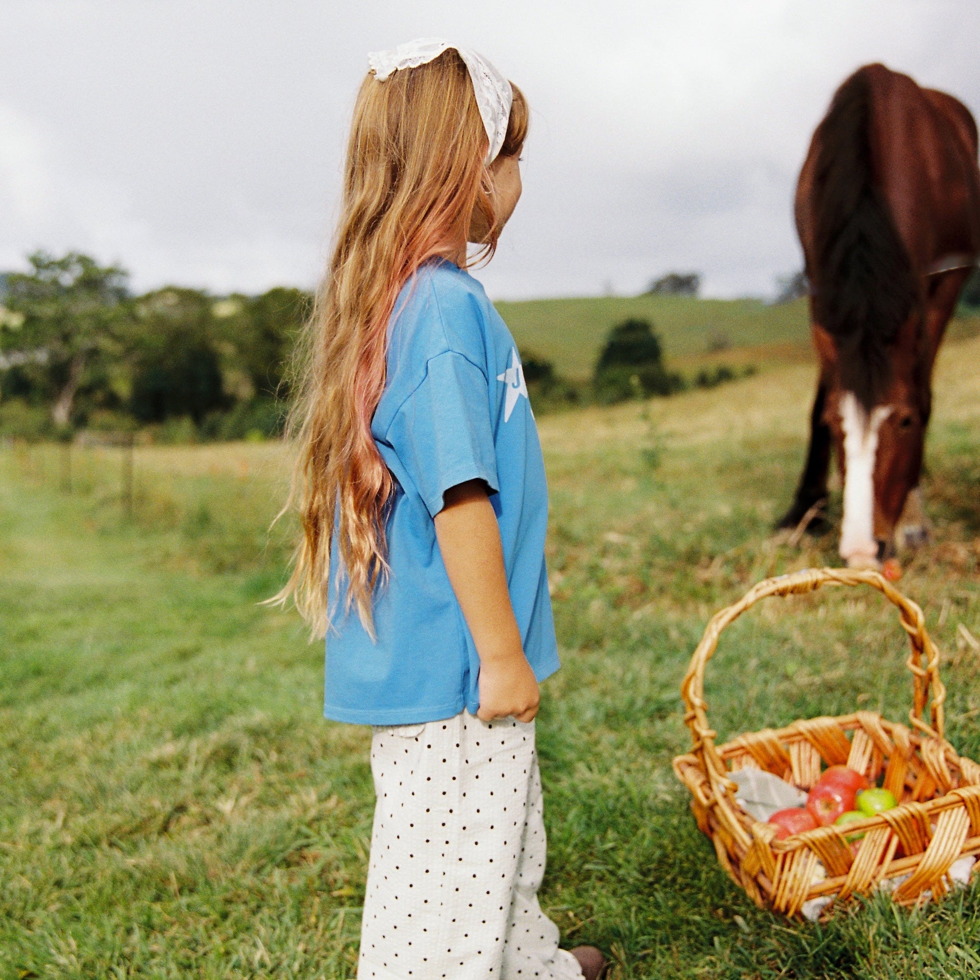 Side profile of azure blue Star Tee with white star print in outdoor setting