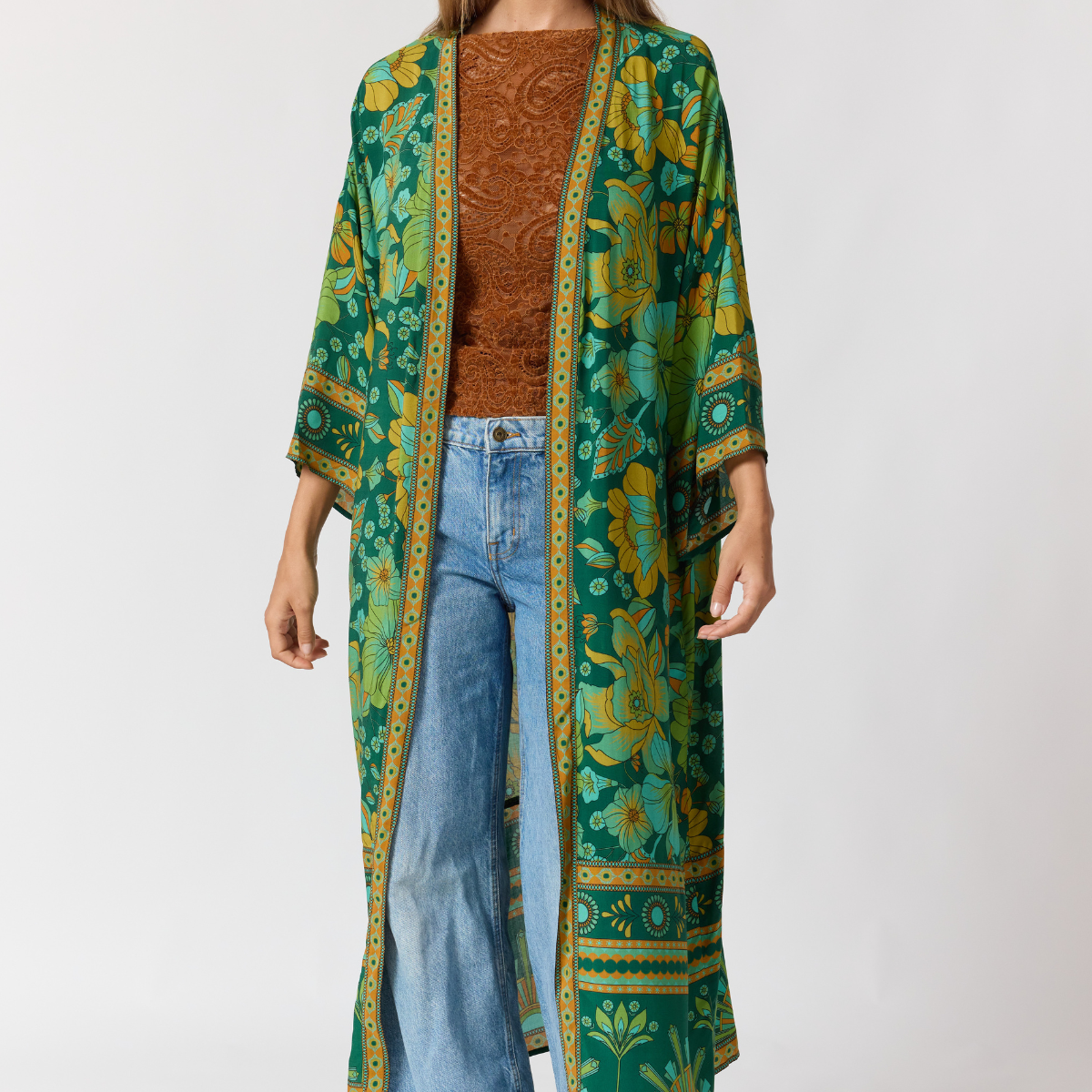 Woman wearing emerald green open front robe over white dress in natural lighting