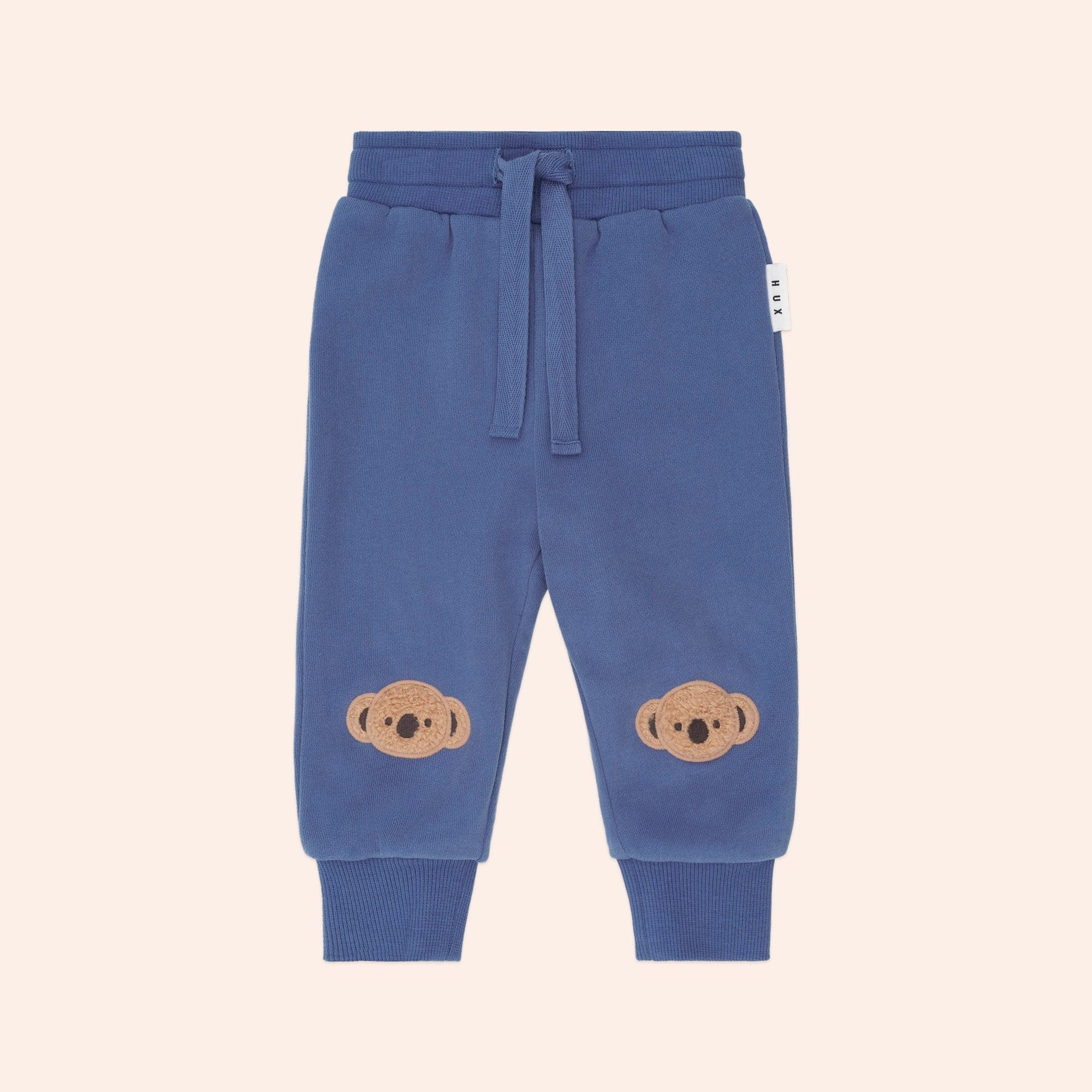 Front view of Huxbaby Kel Koala Trackpant in blue with koala appliques on knees and drawstring waist