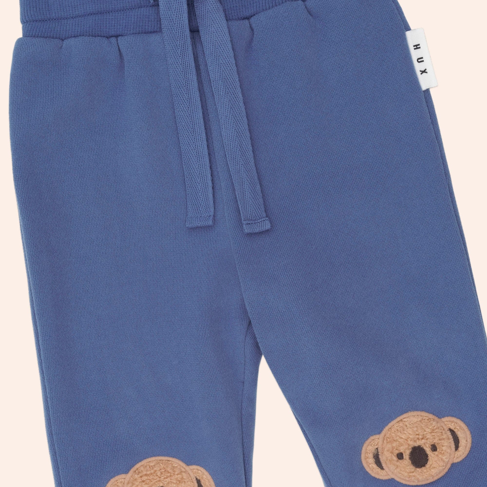 Close-up detail of Huxbaby Kel Koala Trackpant showing drawstring waist and koala face appliques on legs