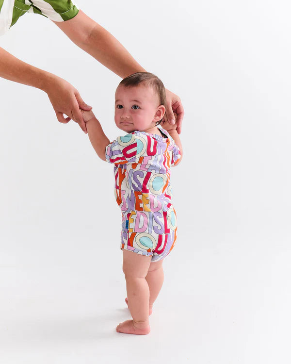 Toddler wearing Kip & Co x The Beatles All You Need Is Love Organic Short Sleeve Romper