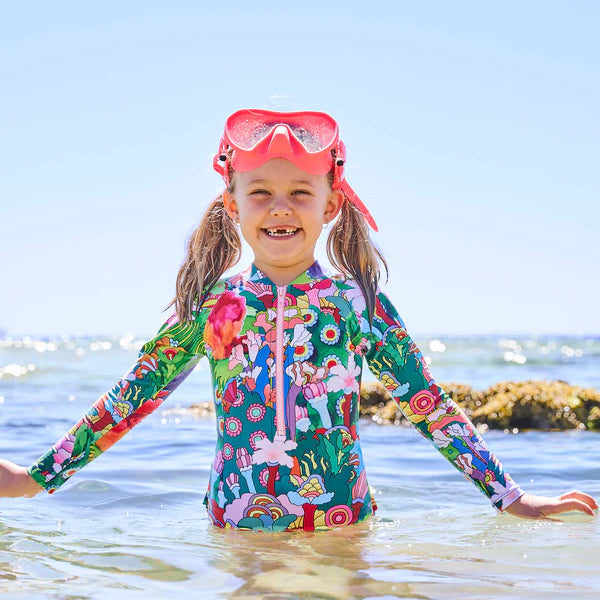 girl at the beach wearing colourful Kip & Co x The Beatles Big Flower Dreamscape Long Sleeve Bathers