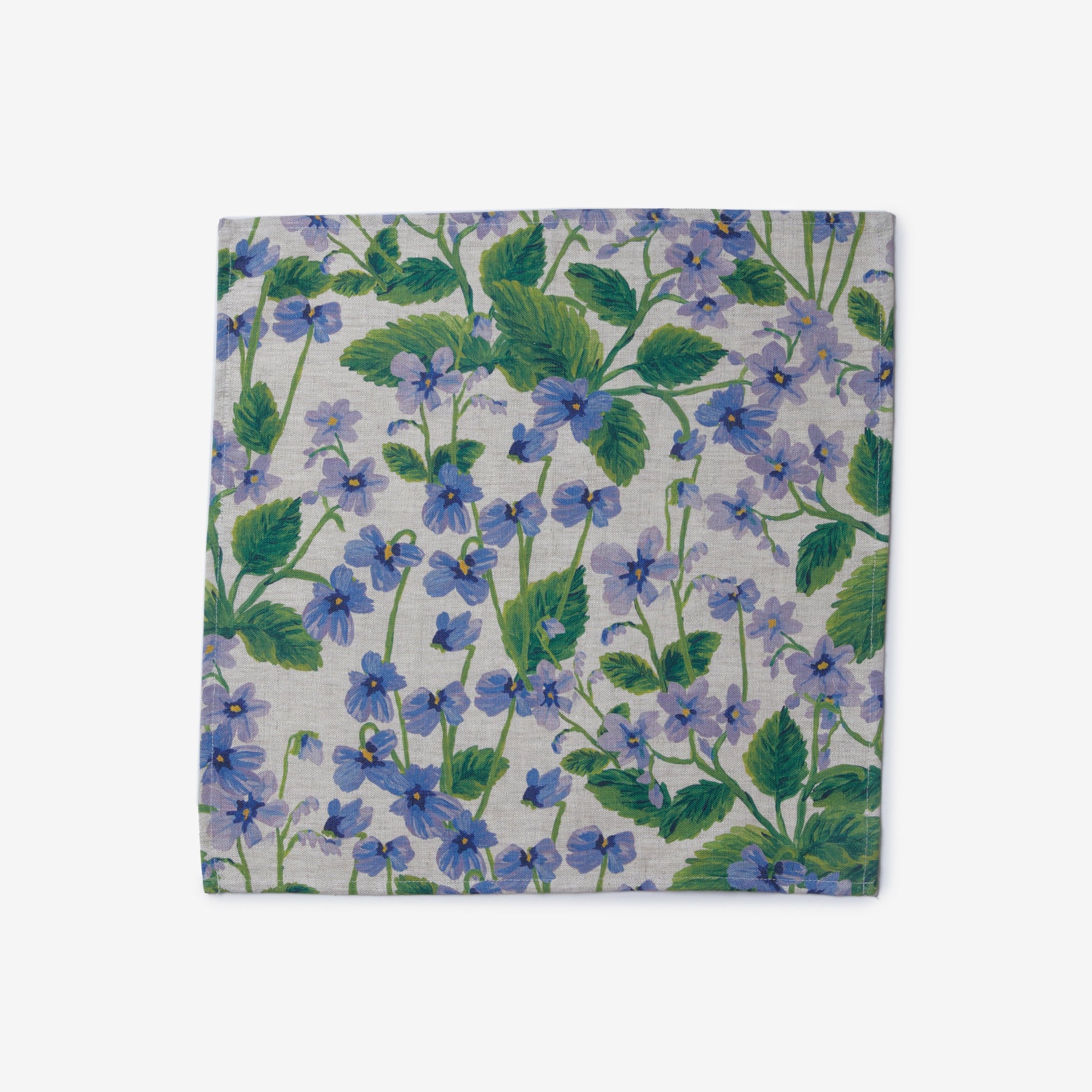 Close-up of Lilas Blue napkins with purple floral pattern and green leaves displayed on dining table