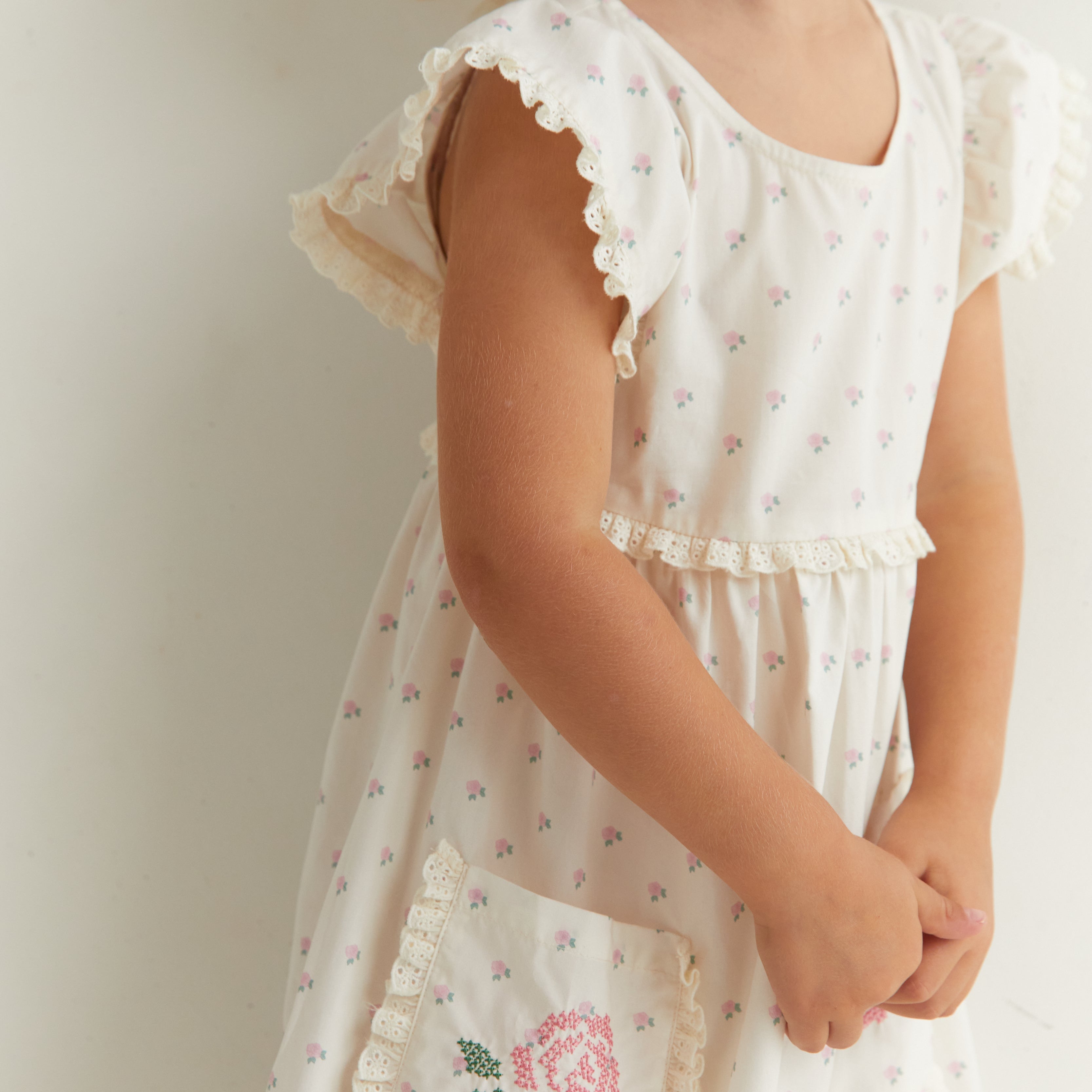 Side detail of Lola Dress showing ruffle sleeves and embroidered rose pocket trim