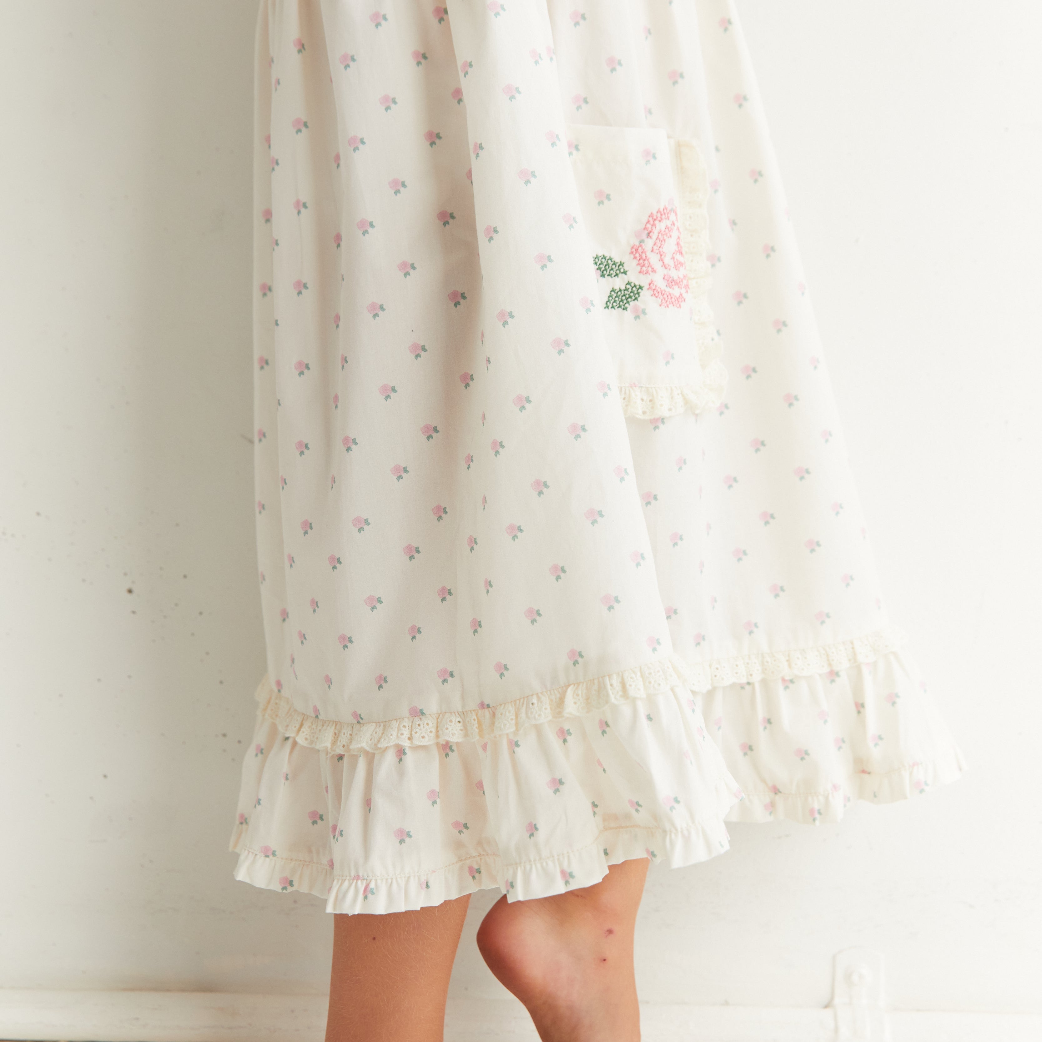 Lower view of Lola Dress showing ruffle hem and embroidered rose pocket detail