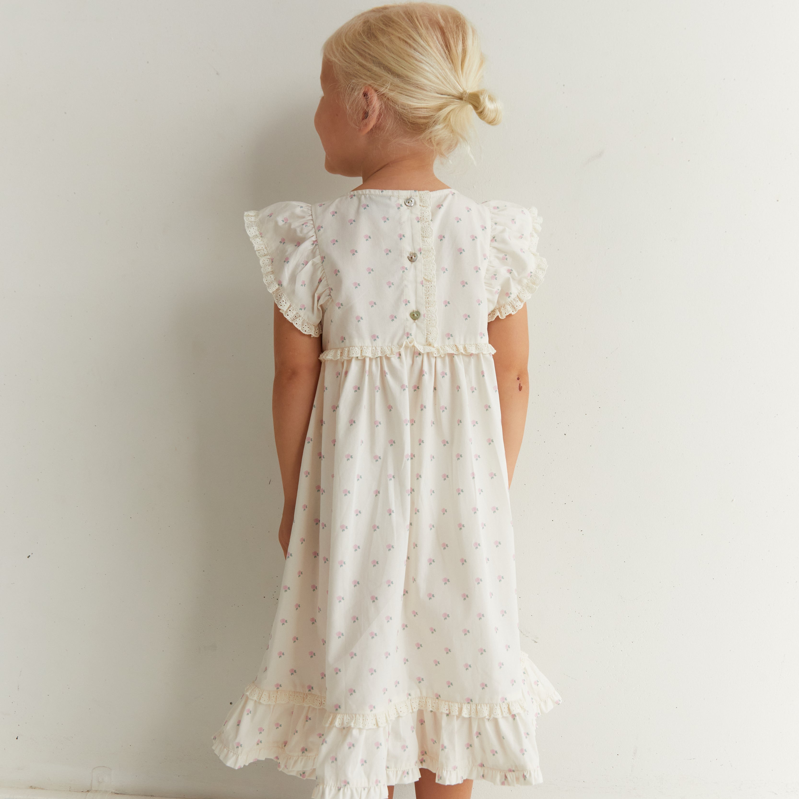 Back view of Lola Dress with roses print showing button closure and ruffle sleeves