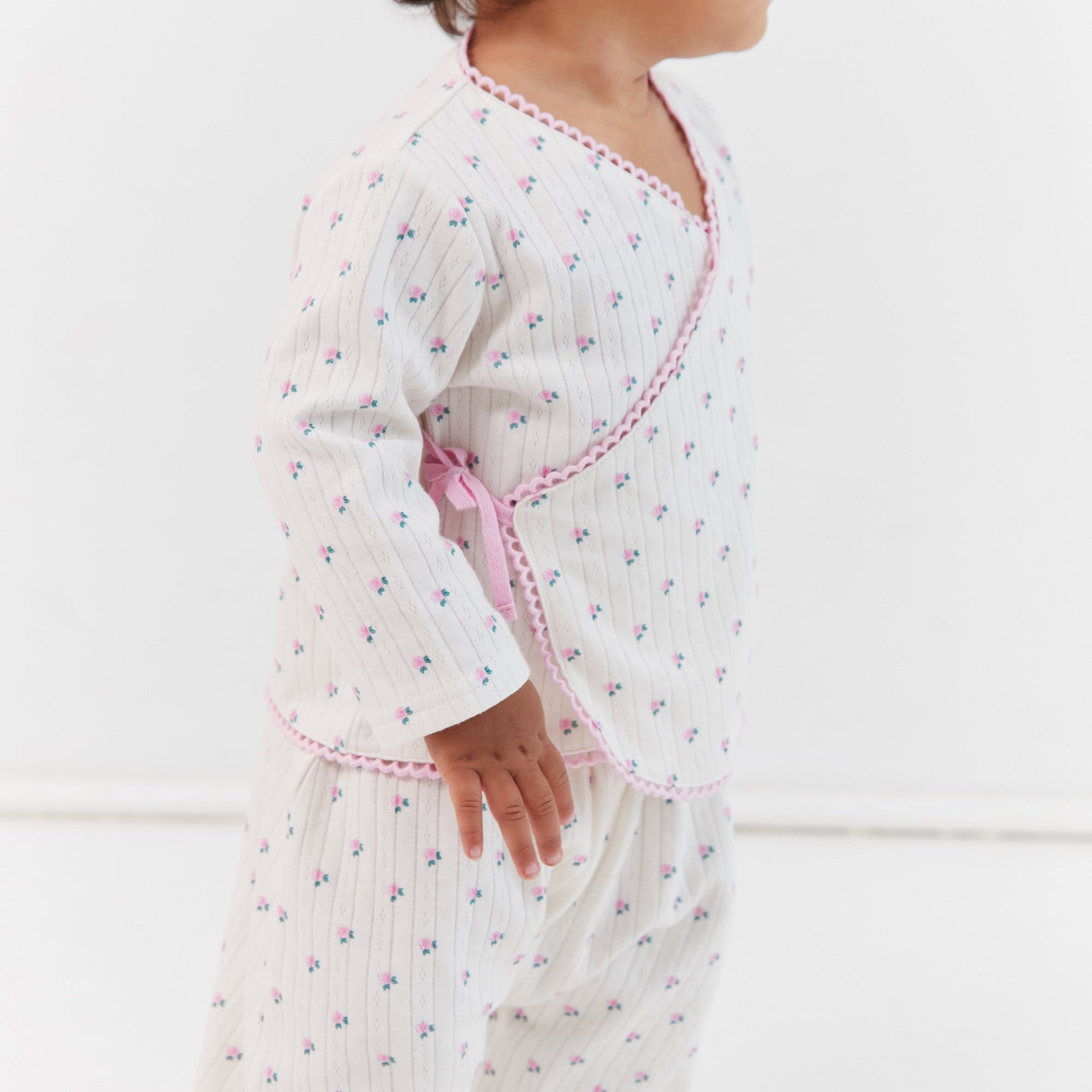 Side profile of child in Lolly Set pajamas with roses print and wrap tie detail