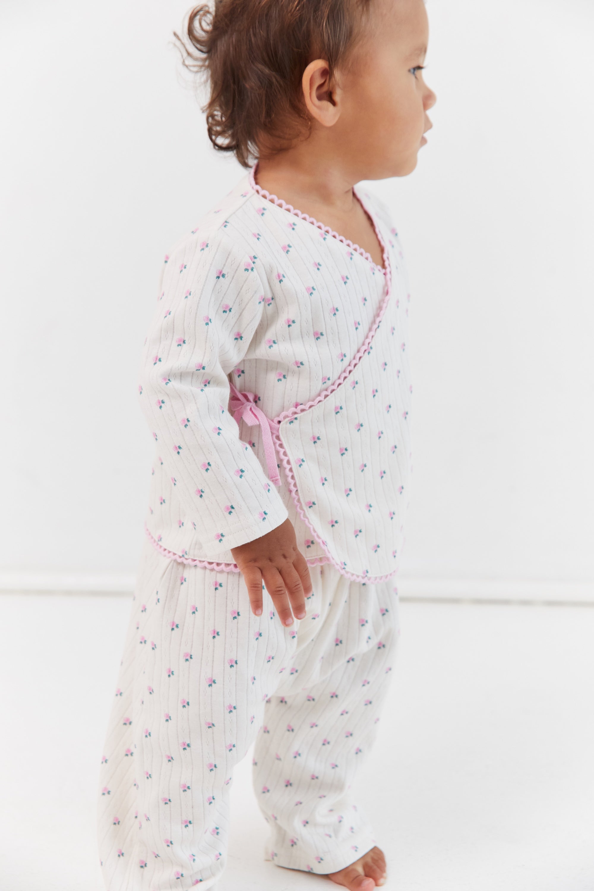Side profile of child in Lolly Set pajamas with roses print and wrap tie detail