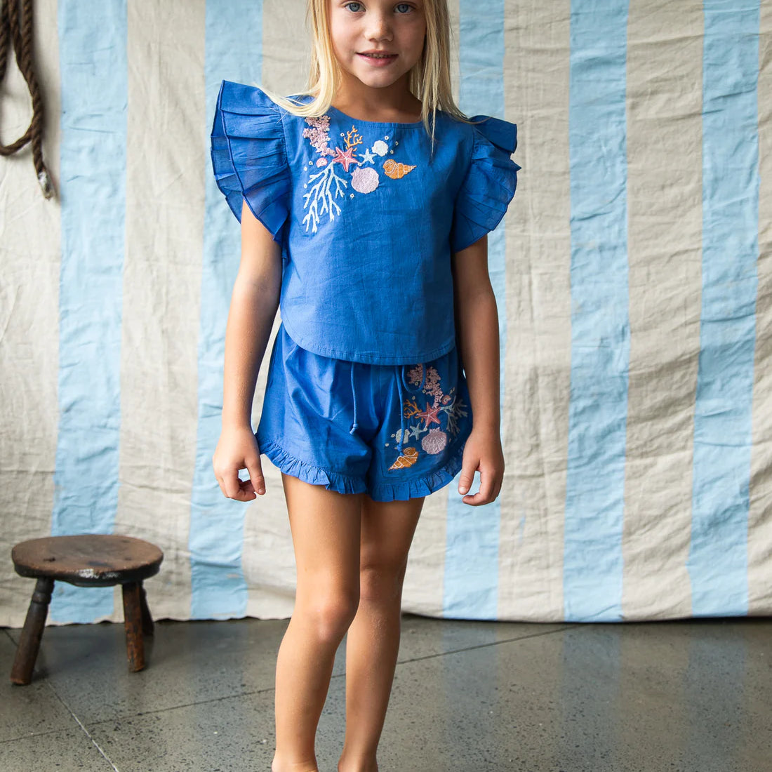 Young girl wearing the blue outfit with coral embroidery by Pearson and Pearson