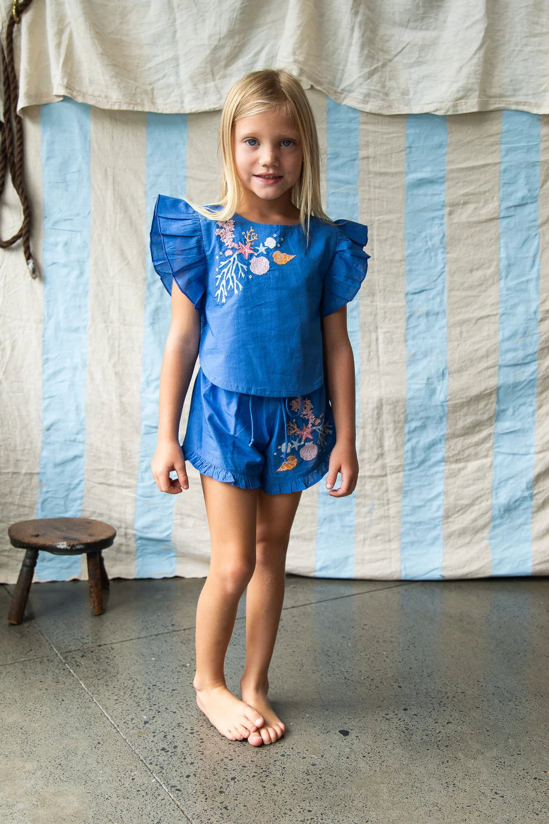Young girl wearing the blue outfit with coral embroidery by Pearson and Pearson