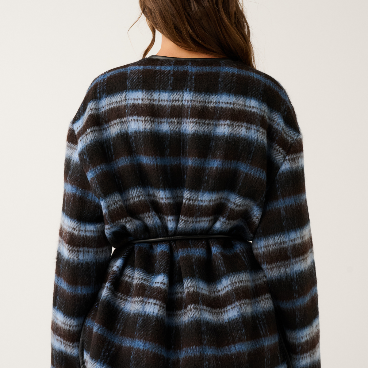 Back view of a blue and brown check oversized jacket with black leather belt tie and fluffy cuffs