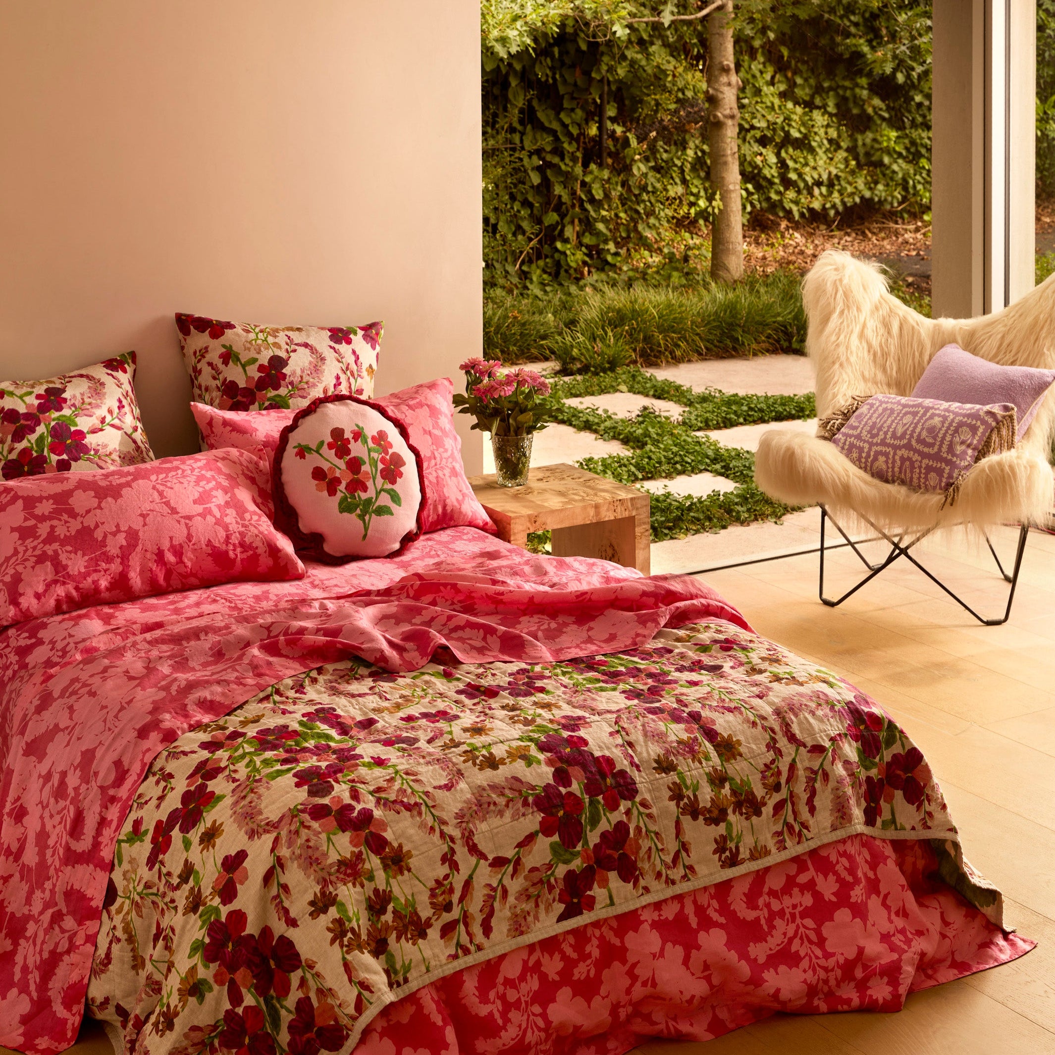 Marigold Leaf floral linen quilted throw on bed showing pink and red flower pattern with green accents