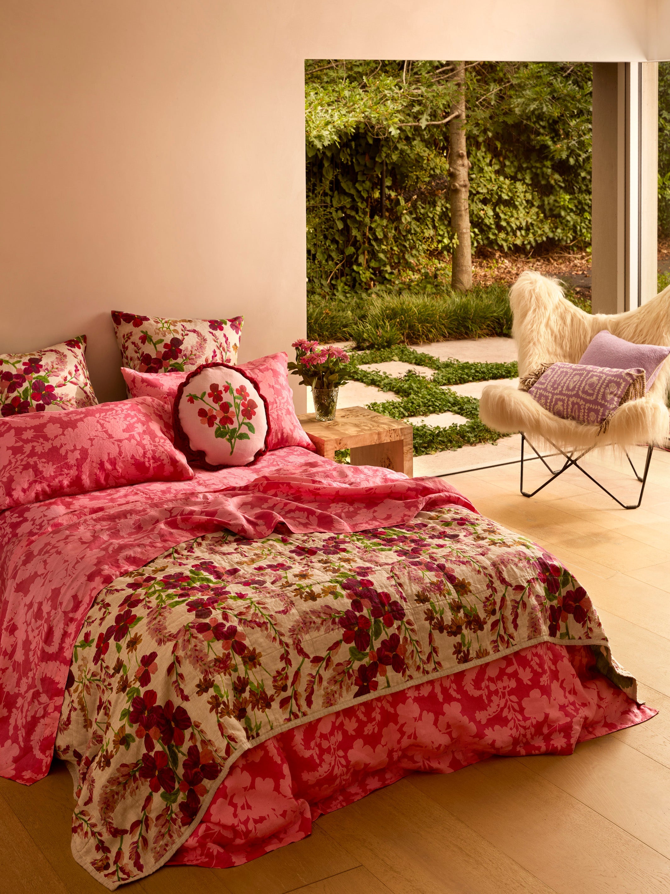 Marigold Leaf floral linen quilted throw on bed showing pink and red flower pattern with green accents