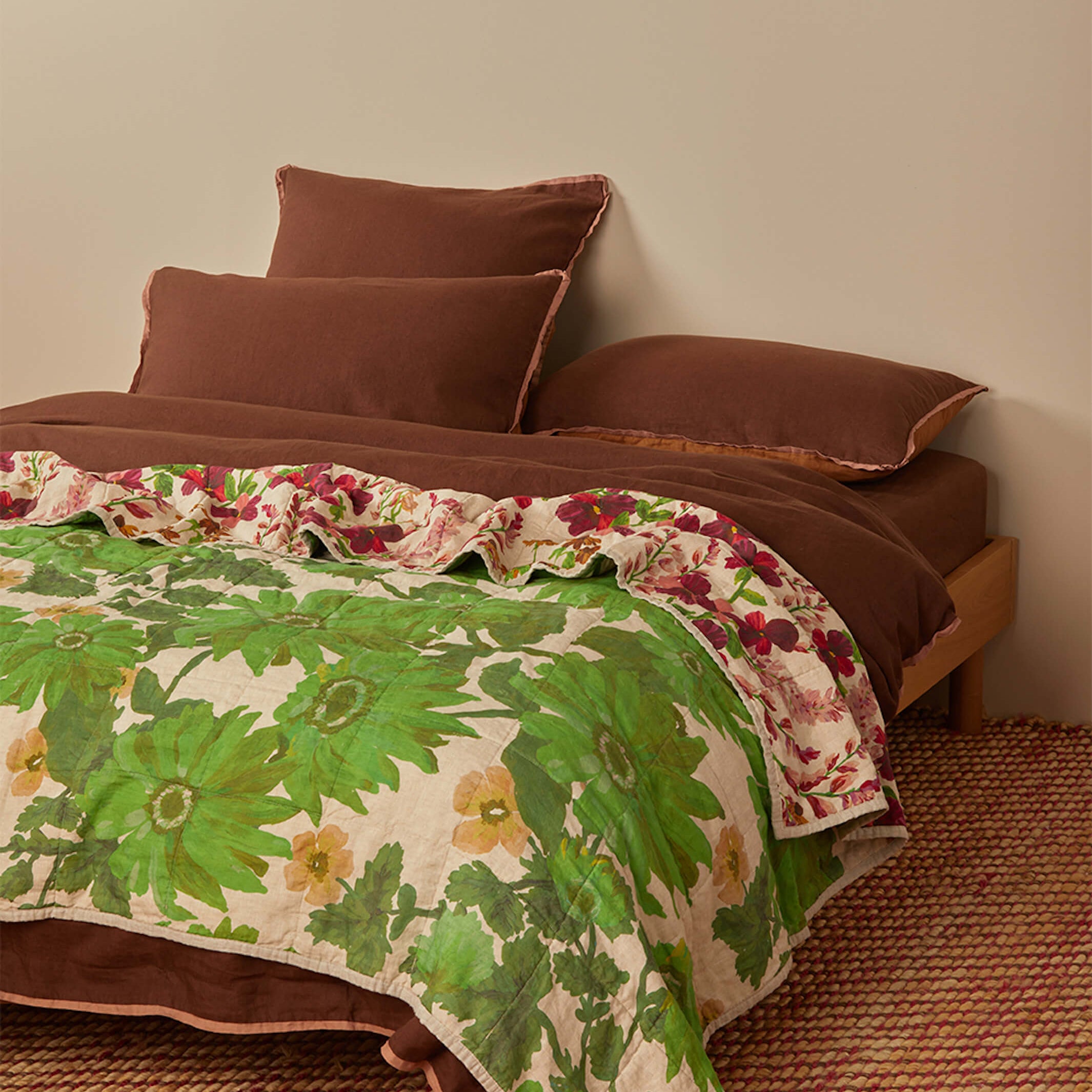 Angled view of Lupin Multi Marigold Leaf quilted throw displaying both green botanical and floral sides