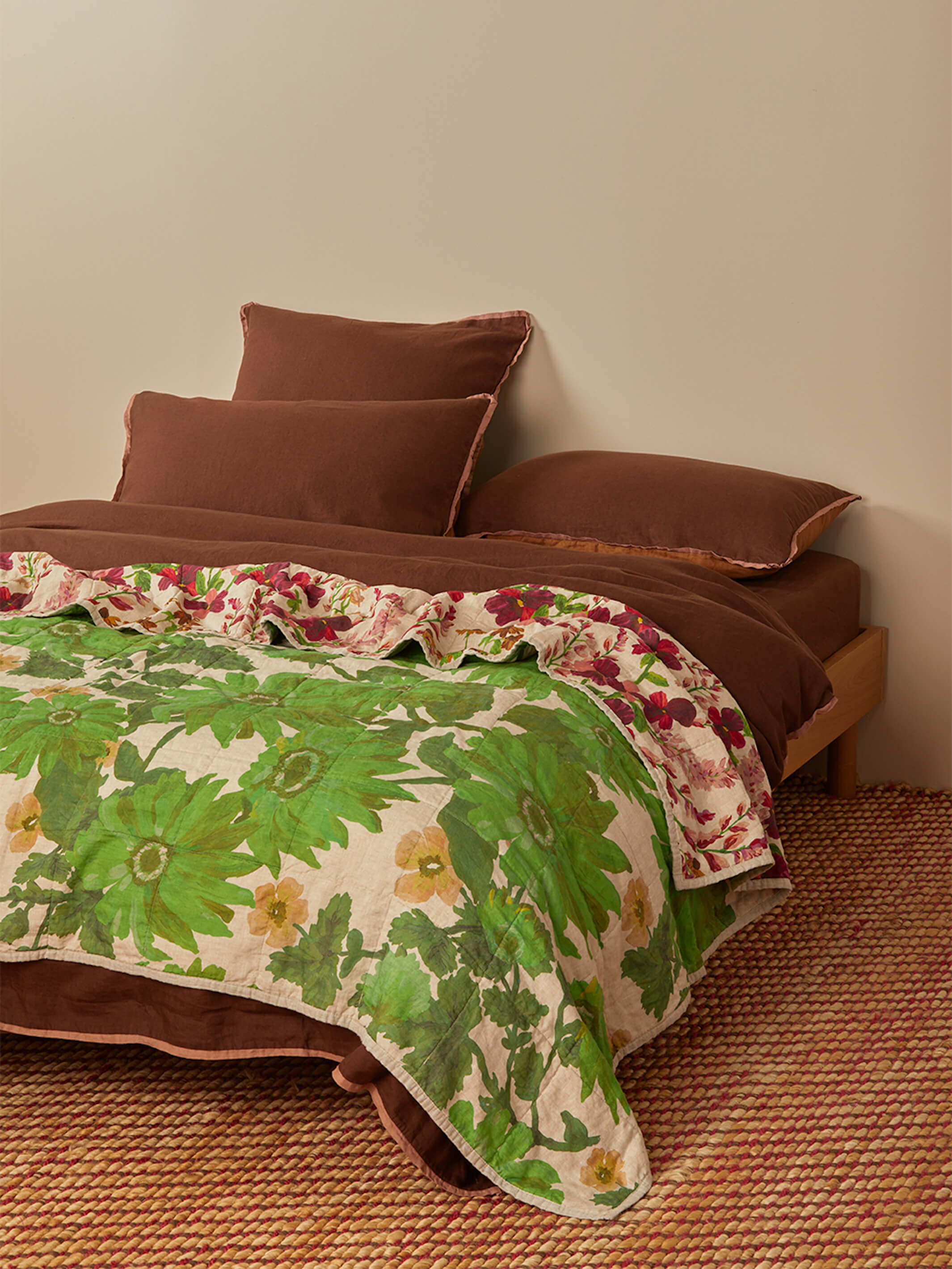 Angled view of Lupin Multi Marigold Leaf quilted throw displaying both green botanical and floral sides
