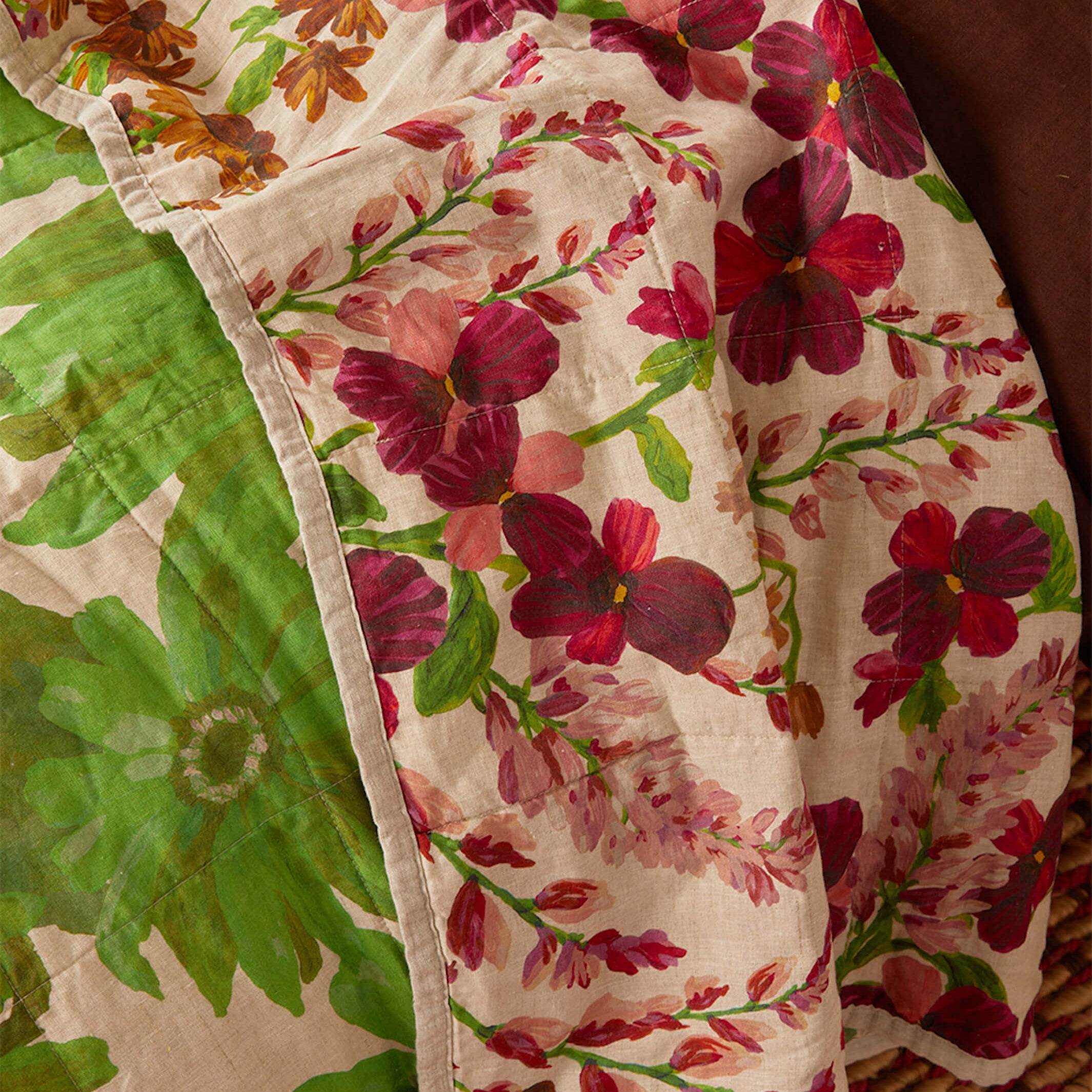 Detail view of Marigold Leaf quilted throw edge showing red floral pattern and stitched binding