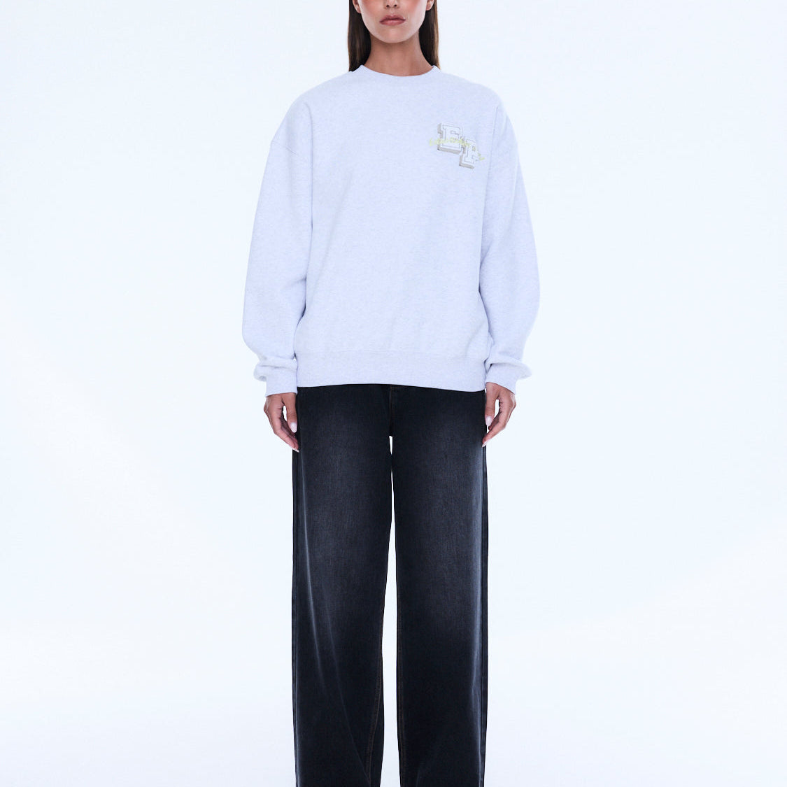 Front view of white oversized sweater showing relaxed fit and embroidered chest detail