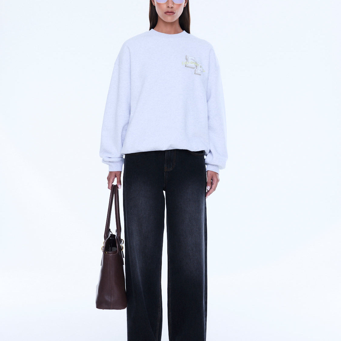 Front view of white Mila Oversized Sweater displaying loose fit and embroidered logo