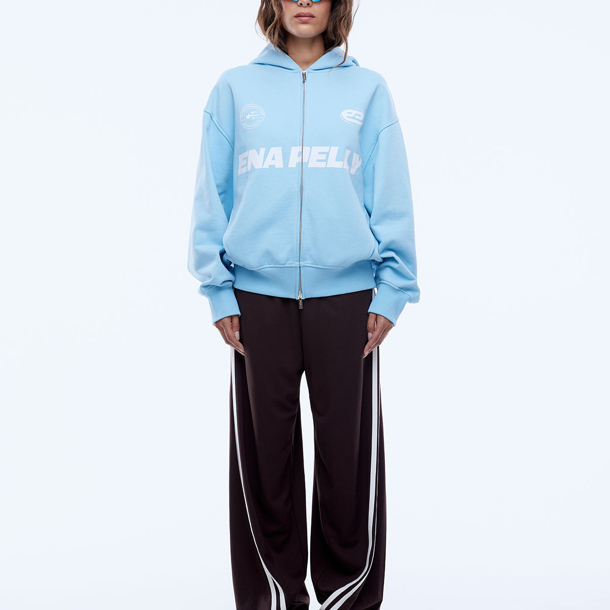 Front view of cloud blue zip-up hoodie displaying multi logo graphics and full zip closure
