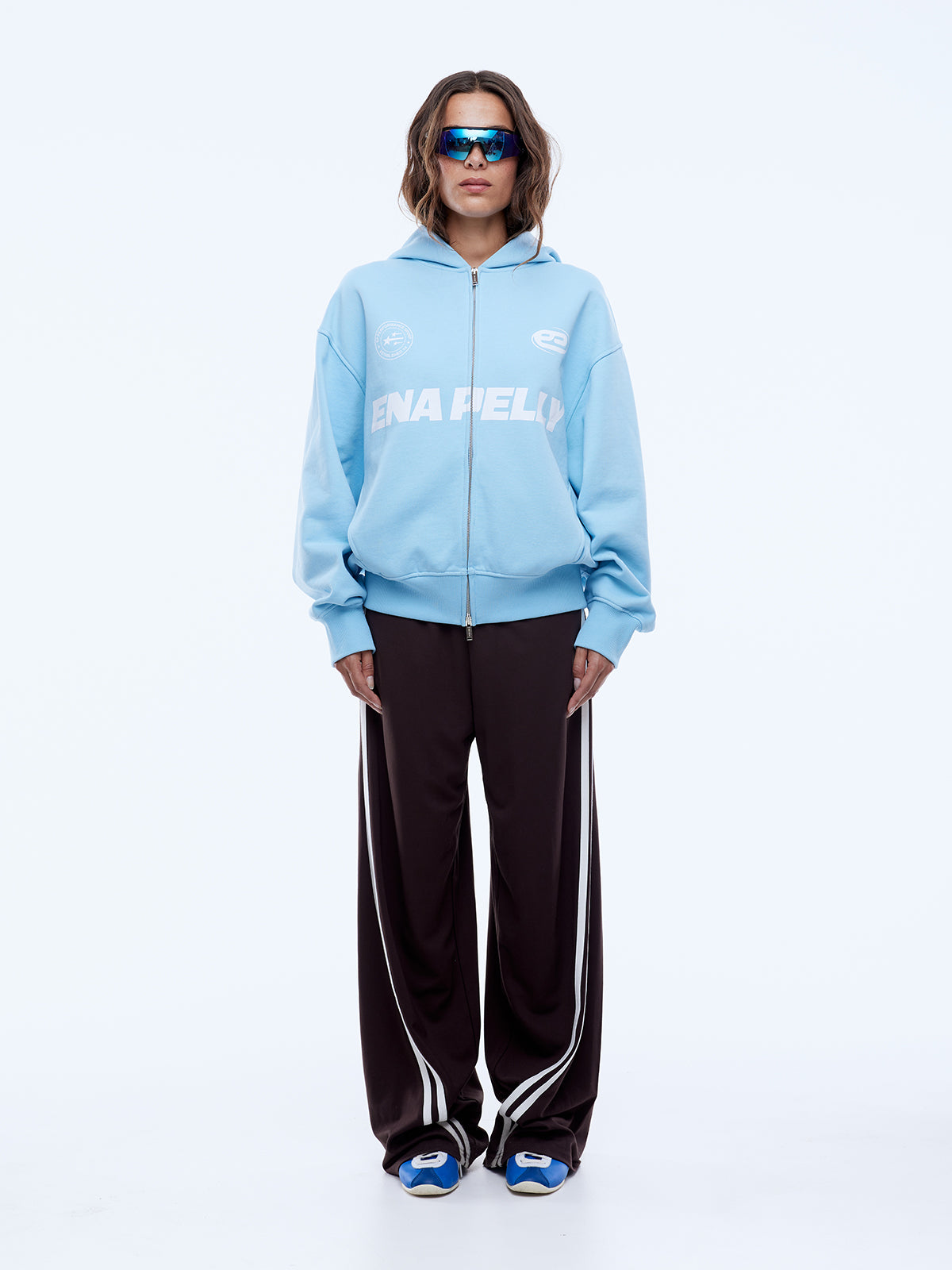 Front view of cloud blue zip-up hoodie displaying multi logo graphics and full zip closure