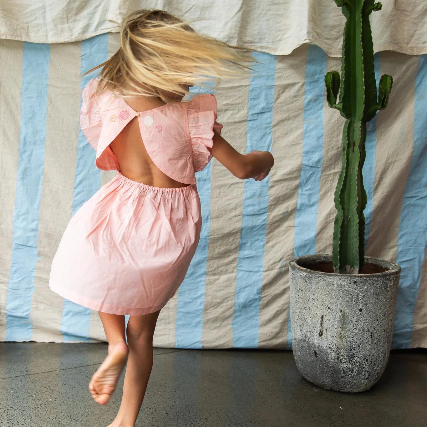 girl wearing open back pink cotton dress by Pearson and Pearson (formerly Bella & Lace ).