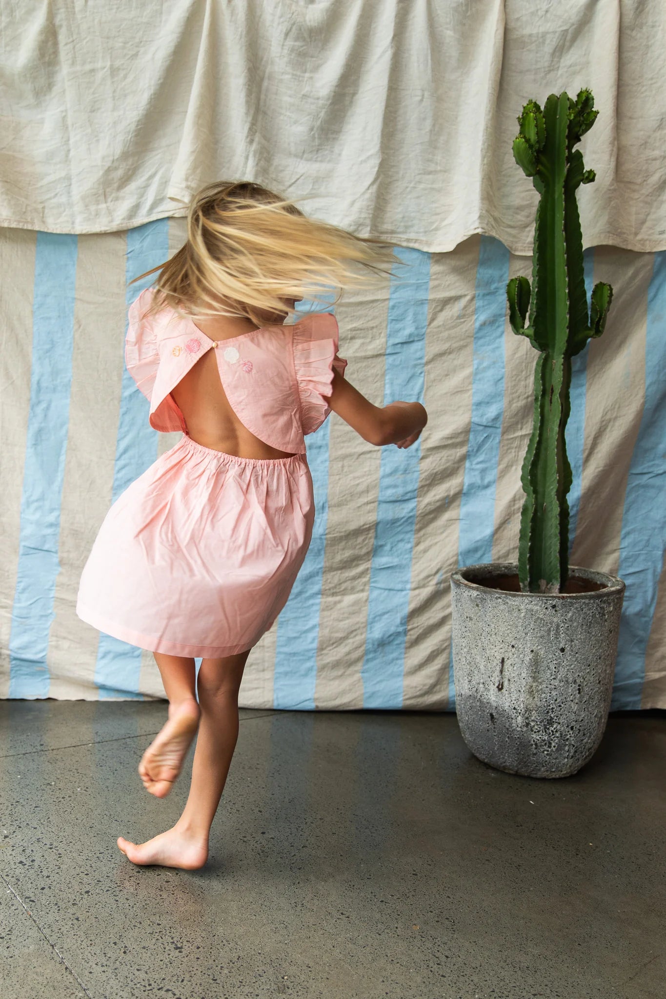 girl wearing open back pink cotton dress by Pearson and Pearson (formerly Bella & Lace ).