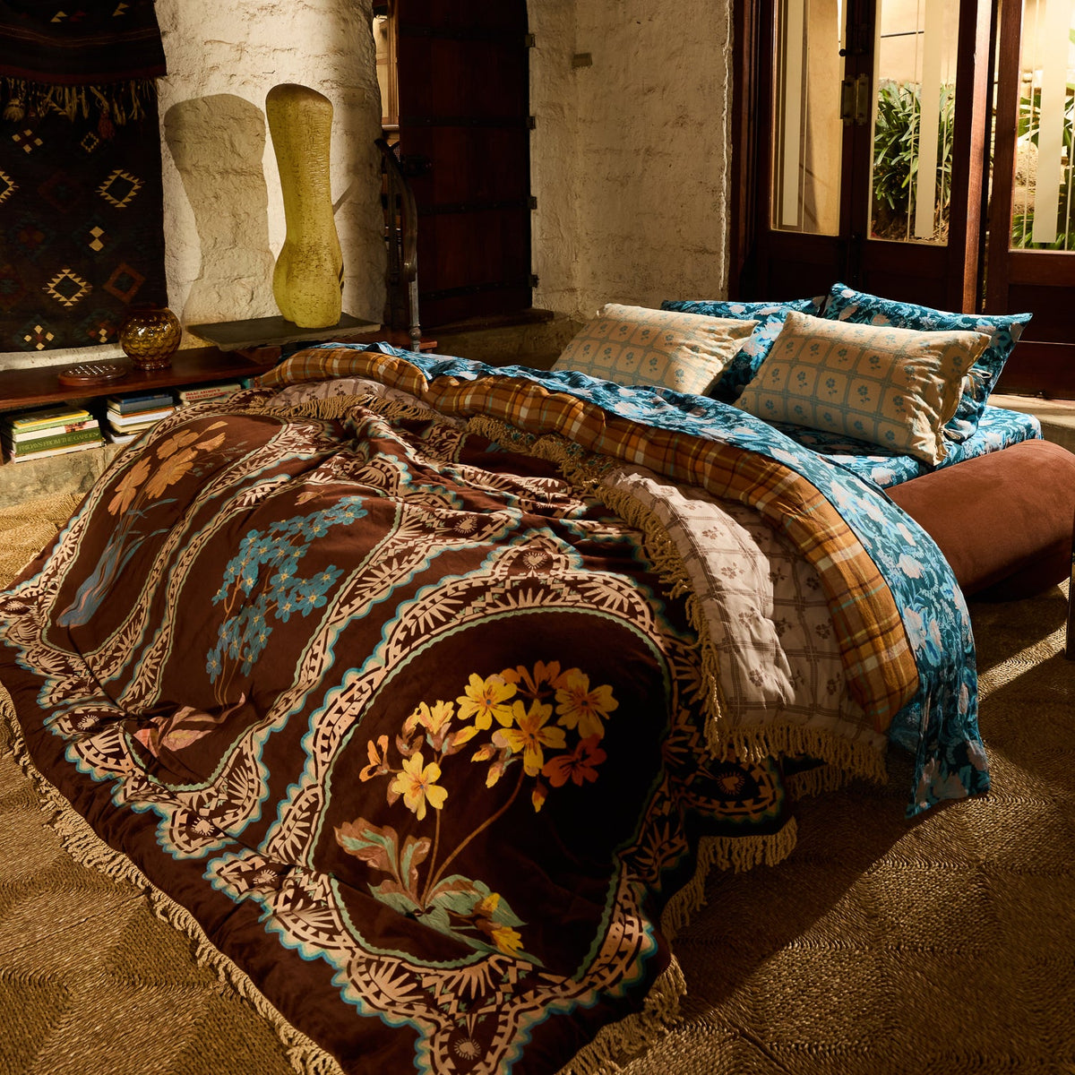 Brown velvet bedcover with botanical medallion print and cream fringe draped across a styled bed in a warm boho bedroom