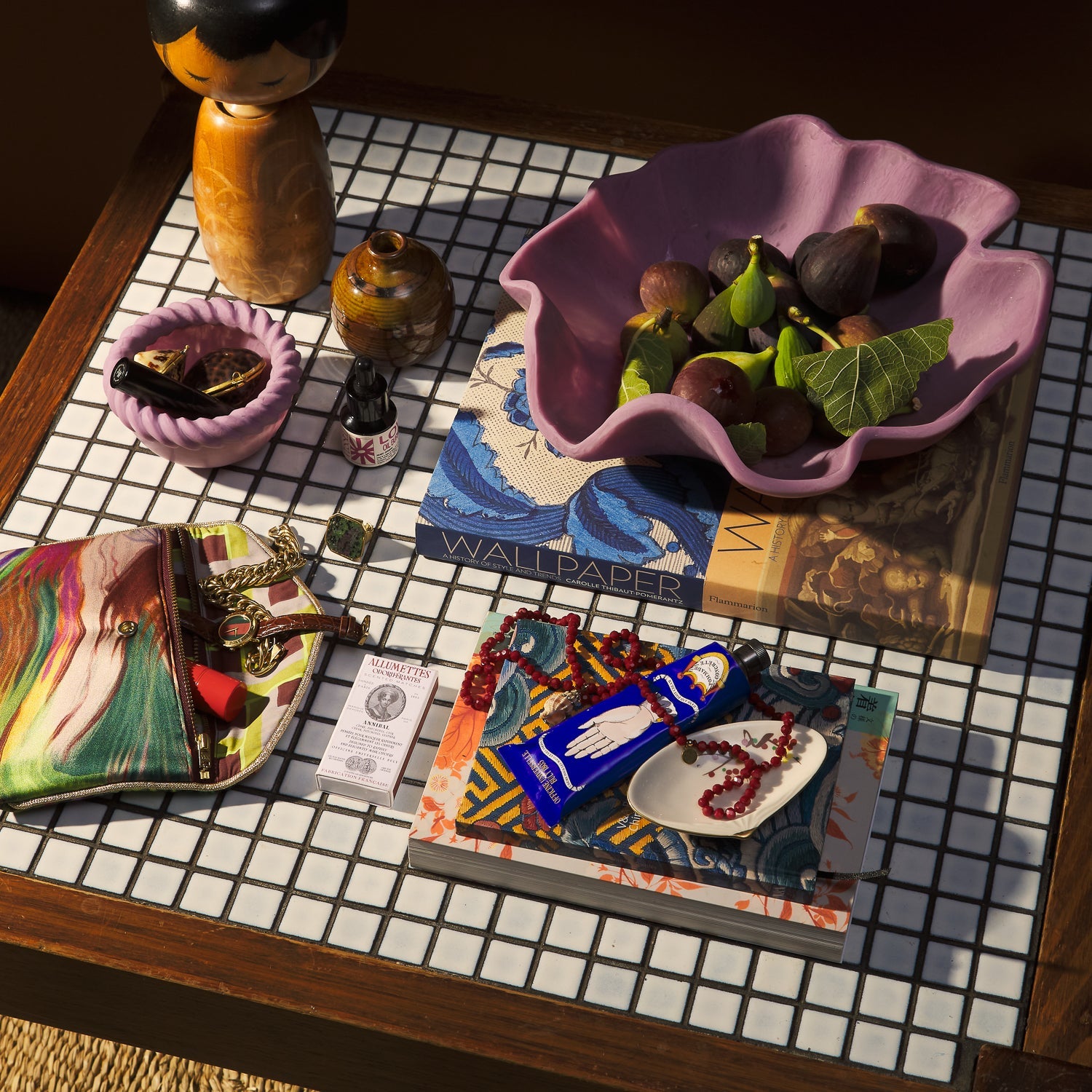 Lifestyle scene with orchid ceramic bowl holding fresh figs on mosaic table with decorative items
