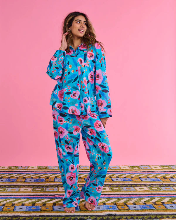 Model looking to the side, wearing Morning harvest 100% organic cotton long sleeve shirt & pant pyjama set by Kip & Co in blue, pink and red floral pattern