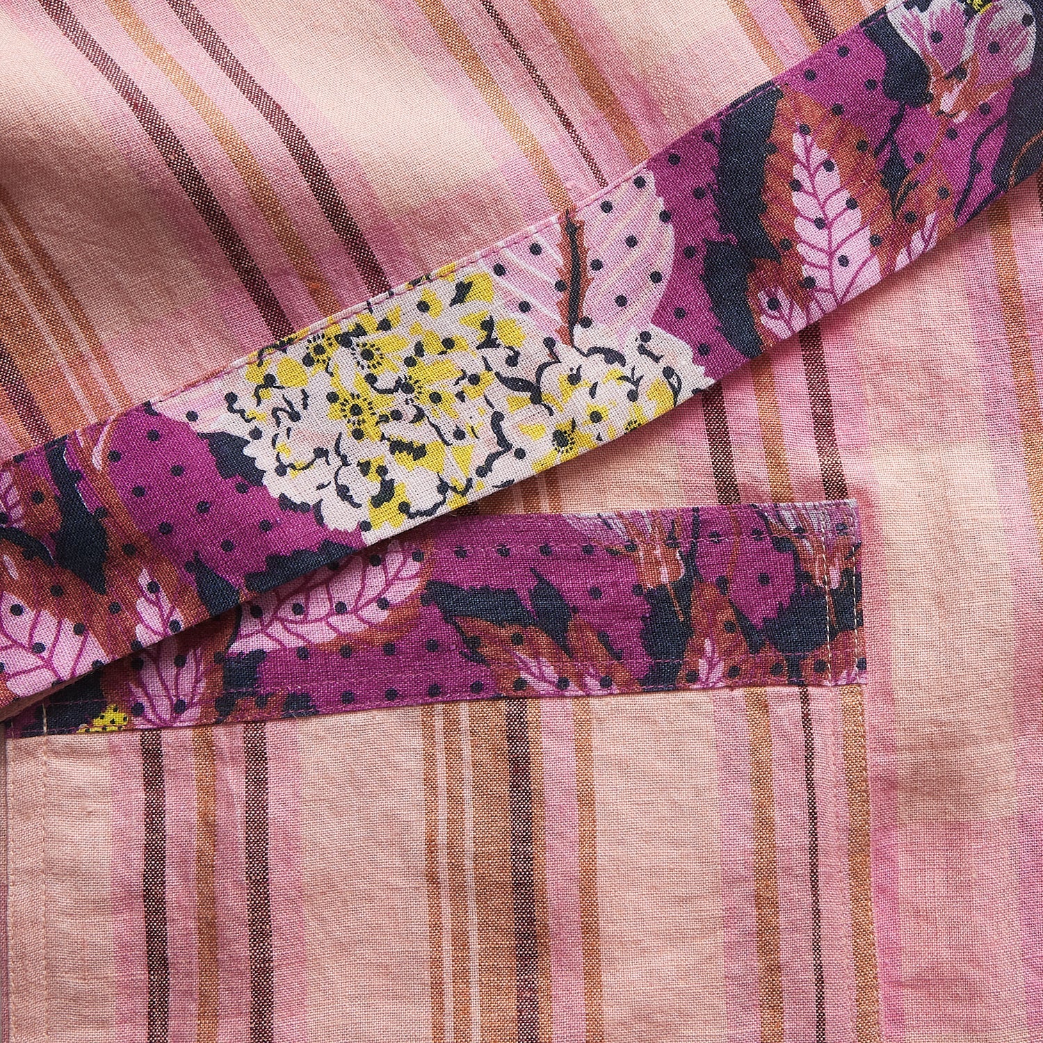 Detail shot of Nicolette Linen Robe fabric showing pink stripes and colorful floral patchwork trim