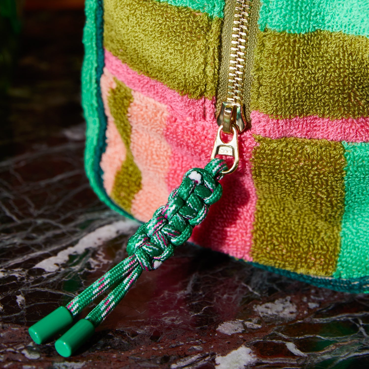 Macro view of gold zipper pull and braided rope cord detail on Nicolette Terry Pouch in Juniper pattern