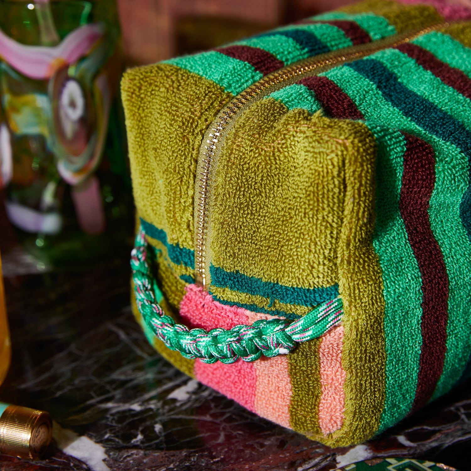 Close-up detail of braided paracord pull tab on colorful striped terry pouch