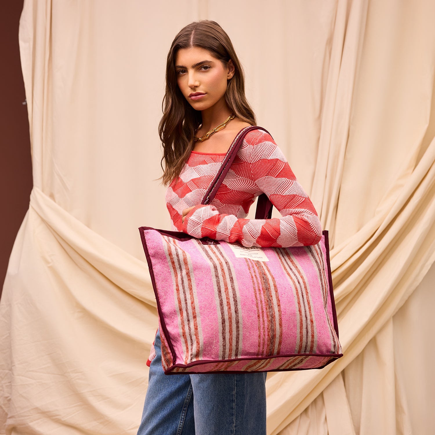 Model carrying Nicolette Woven Tote Bag in Pansy colorway with pink striped pattern and burgundy trim