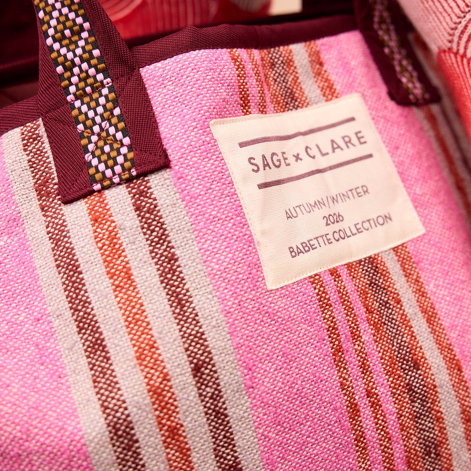 Close-up detail of Sage Clare woven label and burgundy trim on Nicolette Tote Bag pansy striped fabric