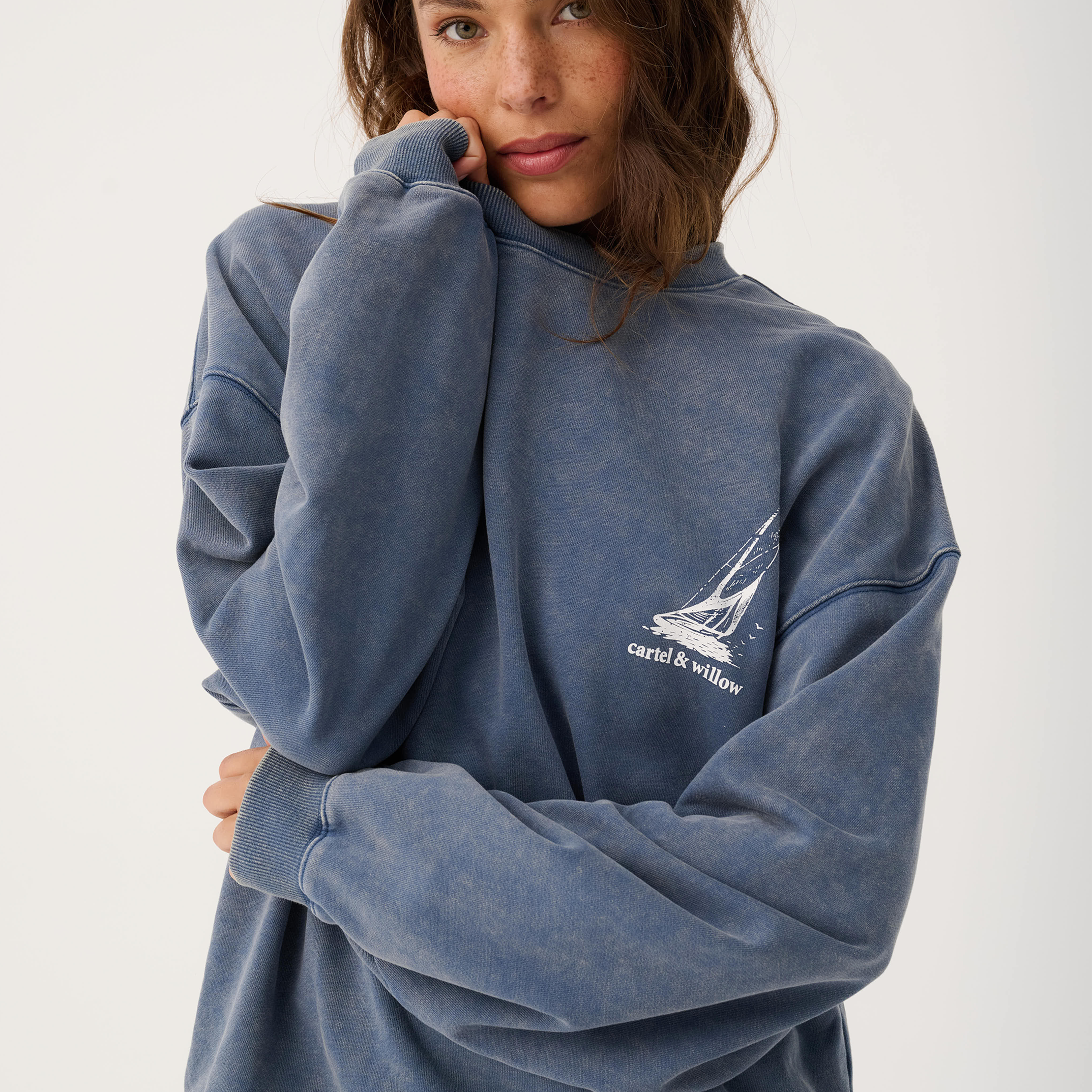 Front view of Nina Sweater in blue showing oversized fit with small sailboat logo on chest