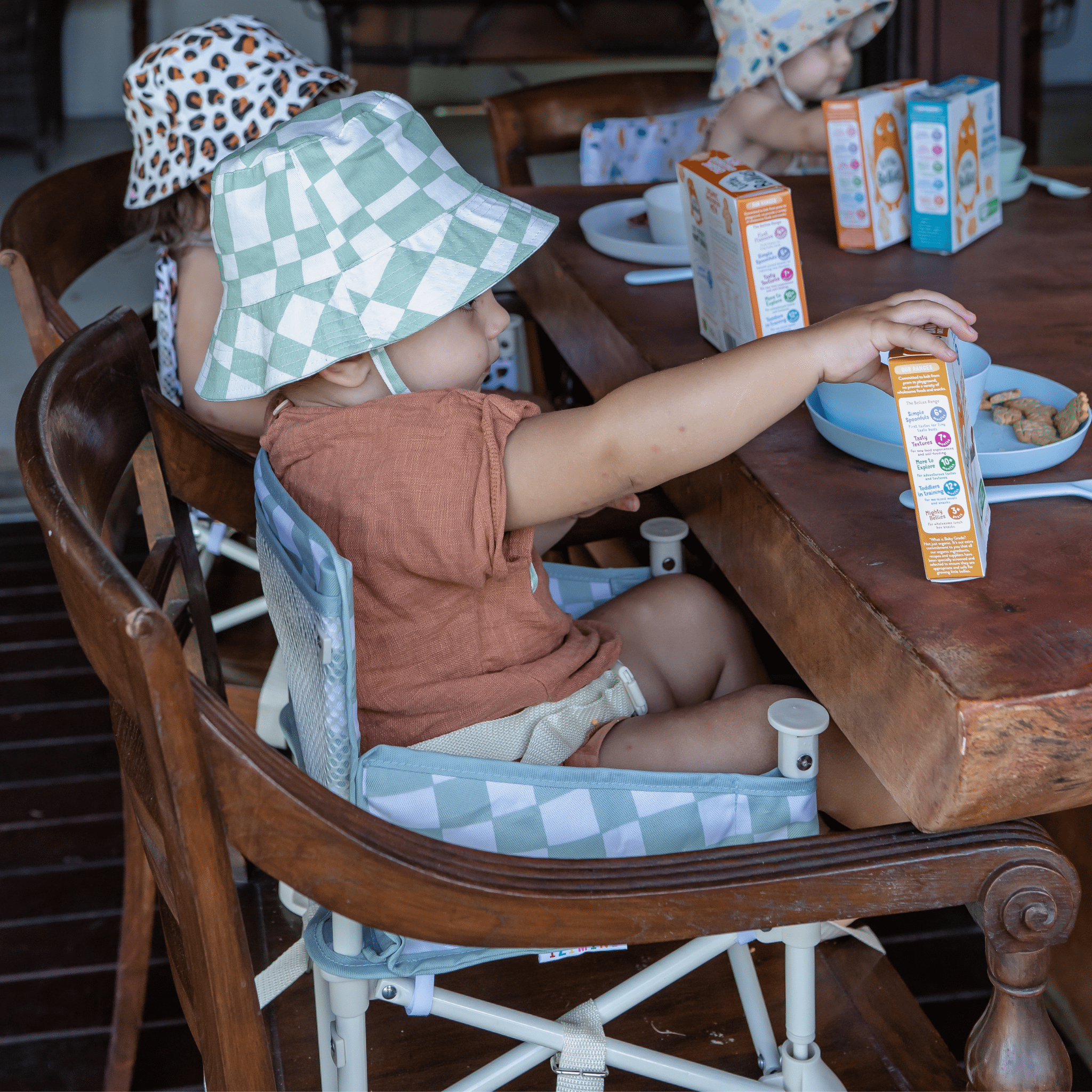 babies using IZIMINI Parker baby chair v2 as a booster seat