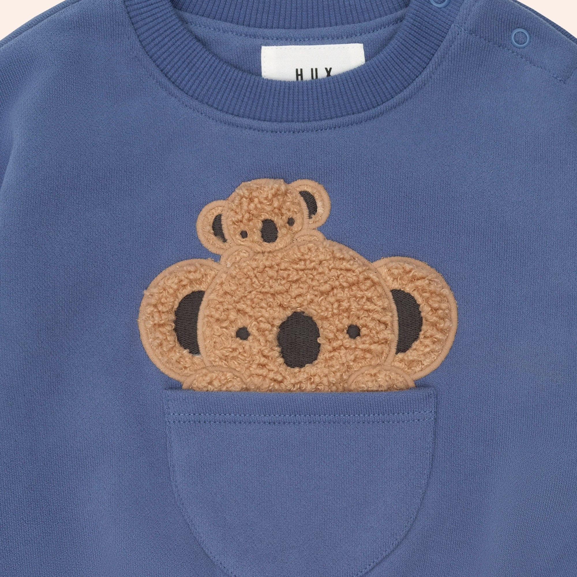 Close-up of Peekaboo Kel Pocket Sweatshirt showing koala applique detail and front pocket with shoulder snaps