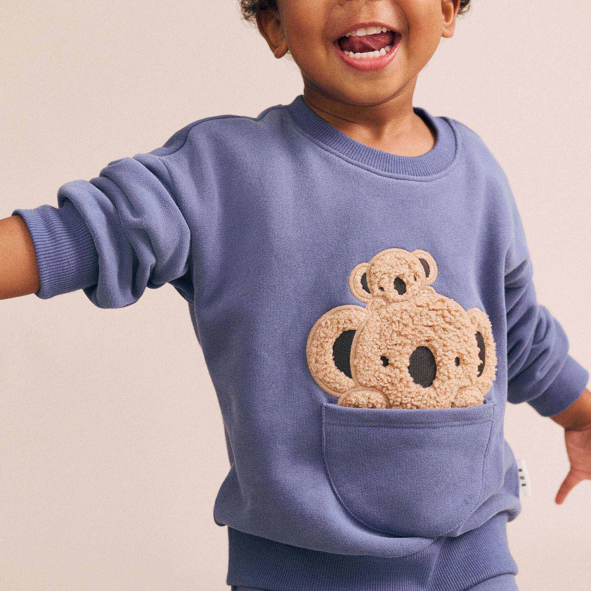 Child modeling blue Peekaboo Kel Pocket Sweatshirt with textured koala applique peeking from front pocket