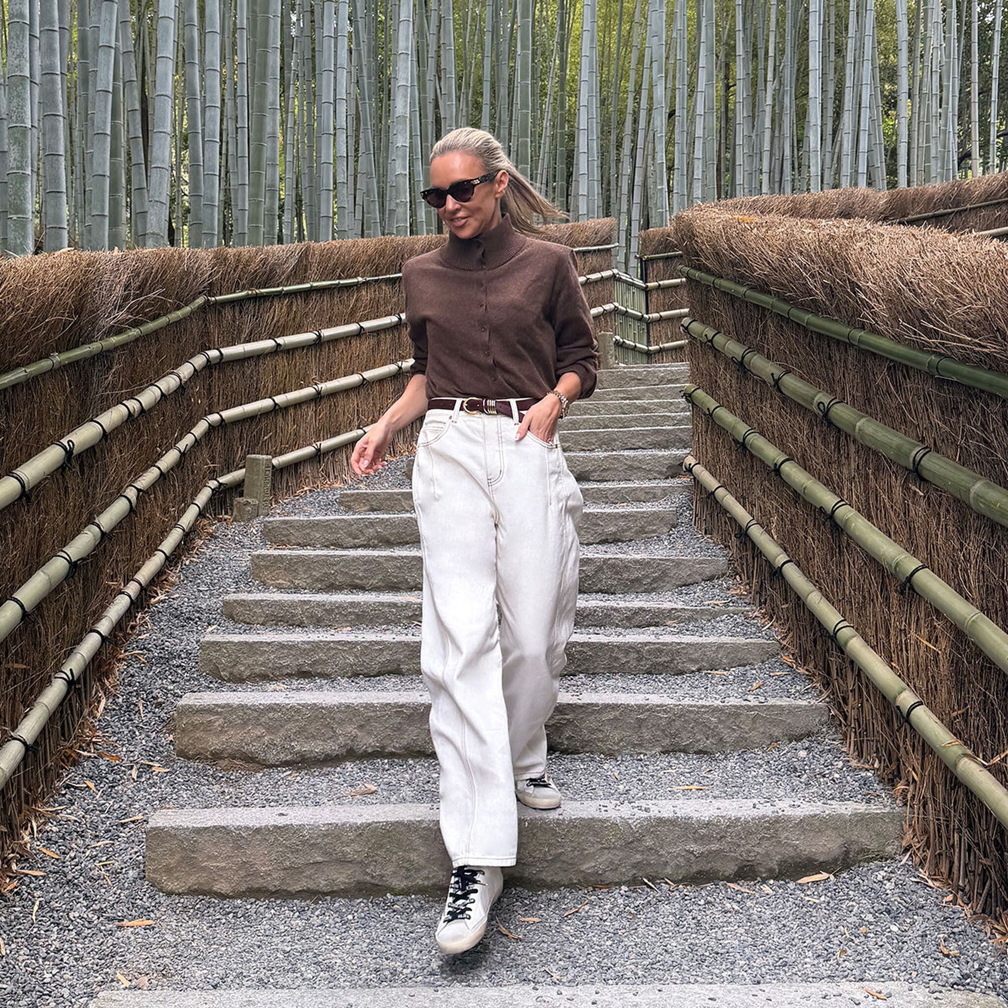 Woman in chocolate marle knit cardigan styled casually walking down bamboo forest pathway