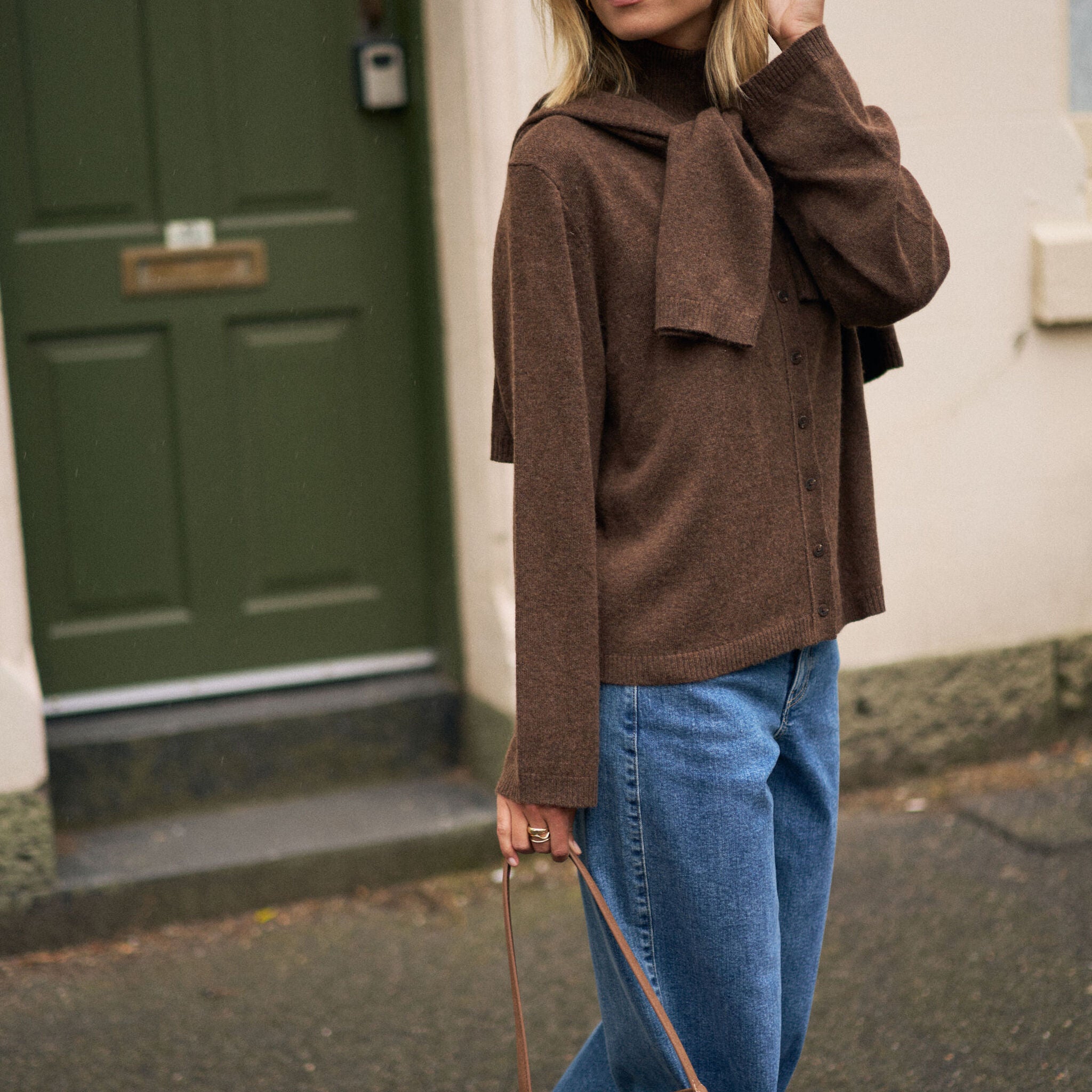 Side profile of woman wearing chocolate marle knit cardigan with high neck and oversized sleeves