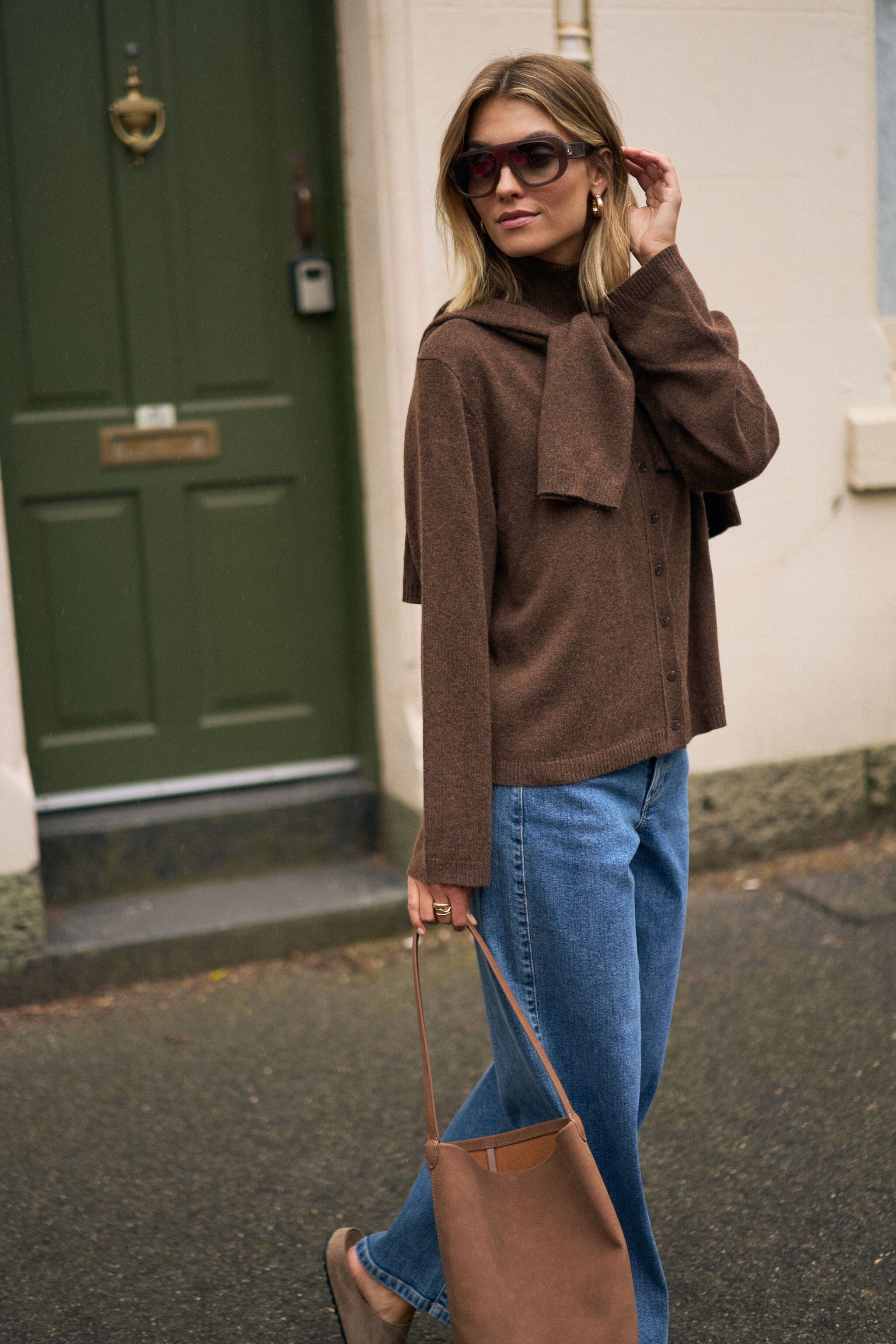Side profile of woman wearing chocolate marle knit cardigan with high neck and oversized sleeves