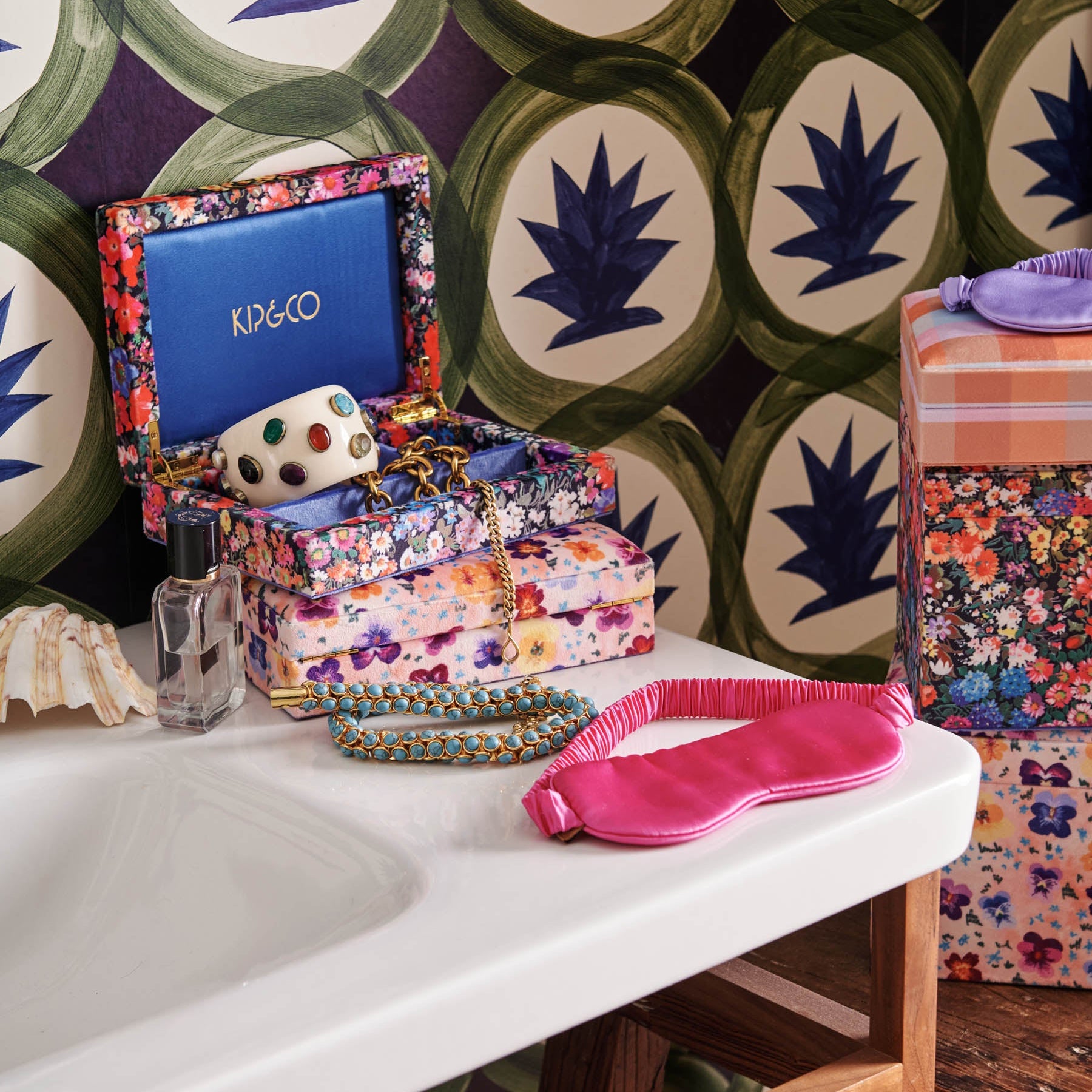 Perfect Pink Silk Eye Mask by Kip & Co styled on white surface with floral jewelry box and accessories