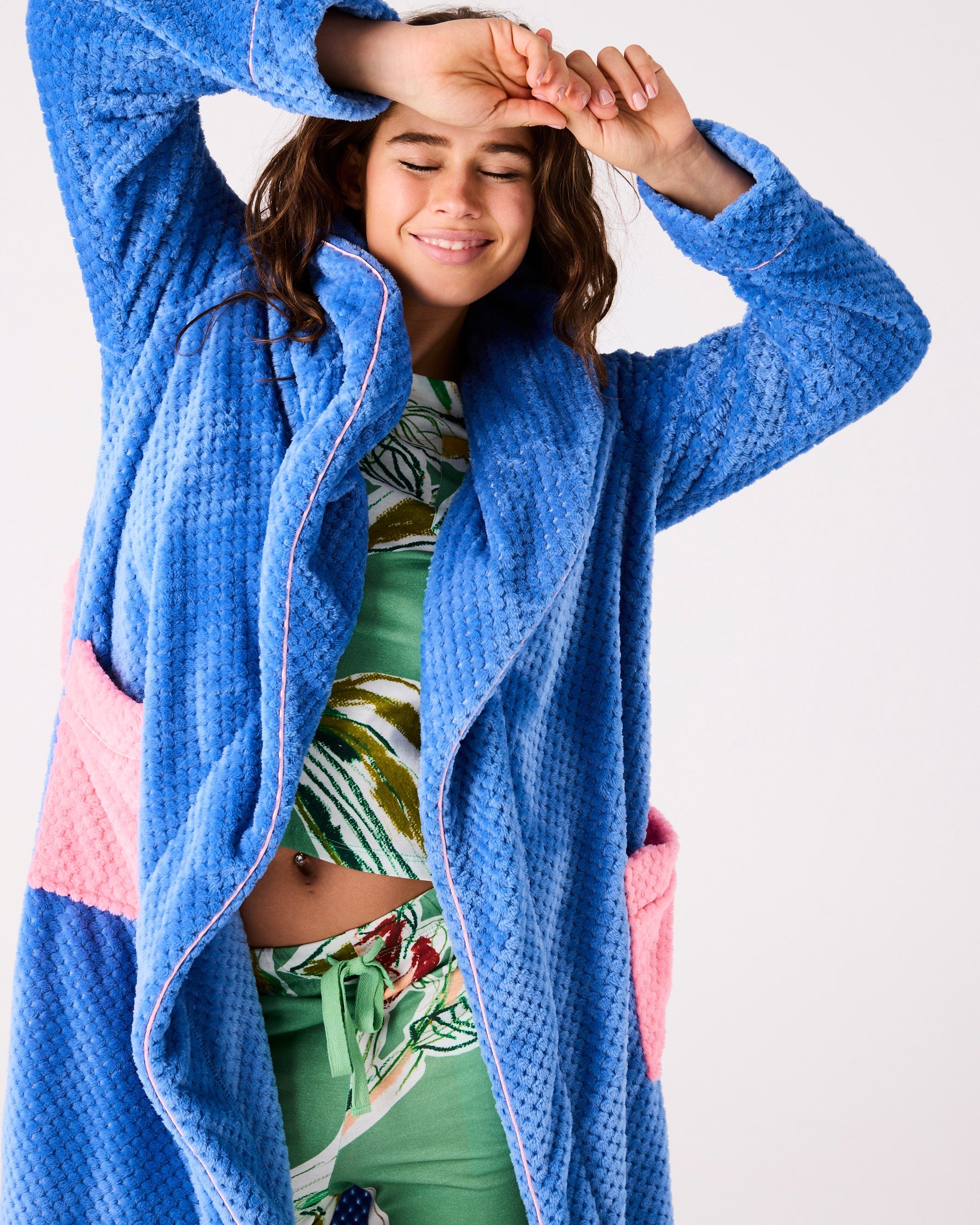Woman in blue Kip & Co cosy robe with arms raised showing comfortable fit and pink contrast trim